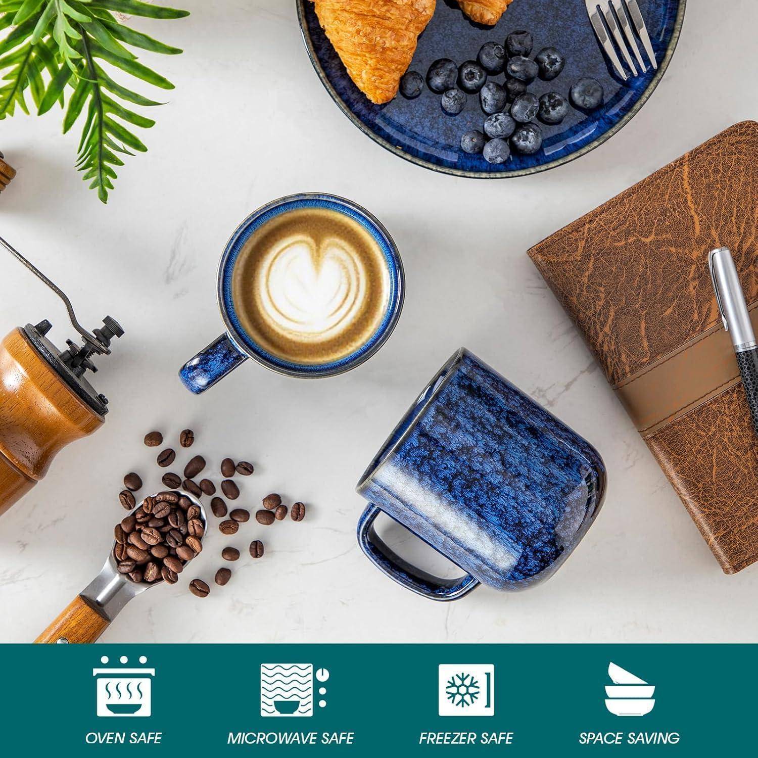 Eine Kaffeetasse, Bohnen, ein Notizbuch mit einem Stift und ein Croissant mit Blaubeeren auf einem Teller. Symbole zeigen an, dass er für Ofen, Mikrowelle und Gefrierschrank geeignet ist und Platz spart.