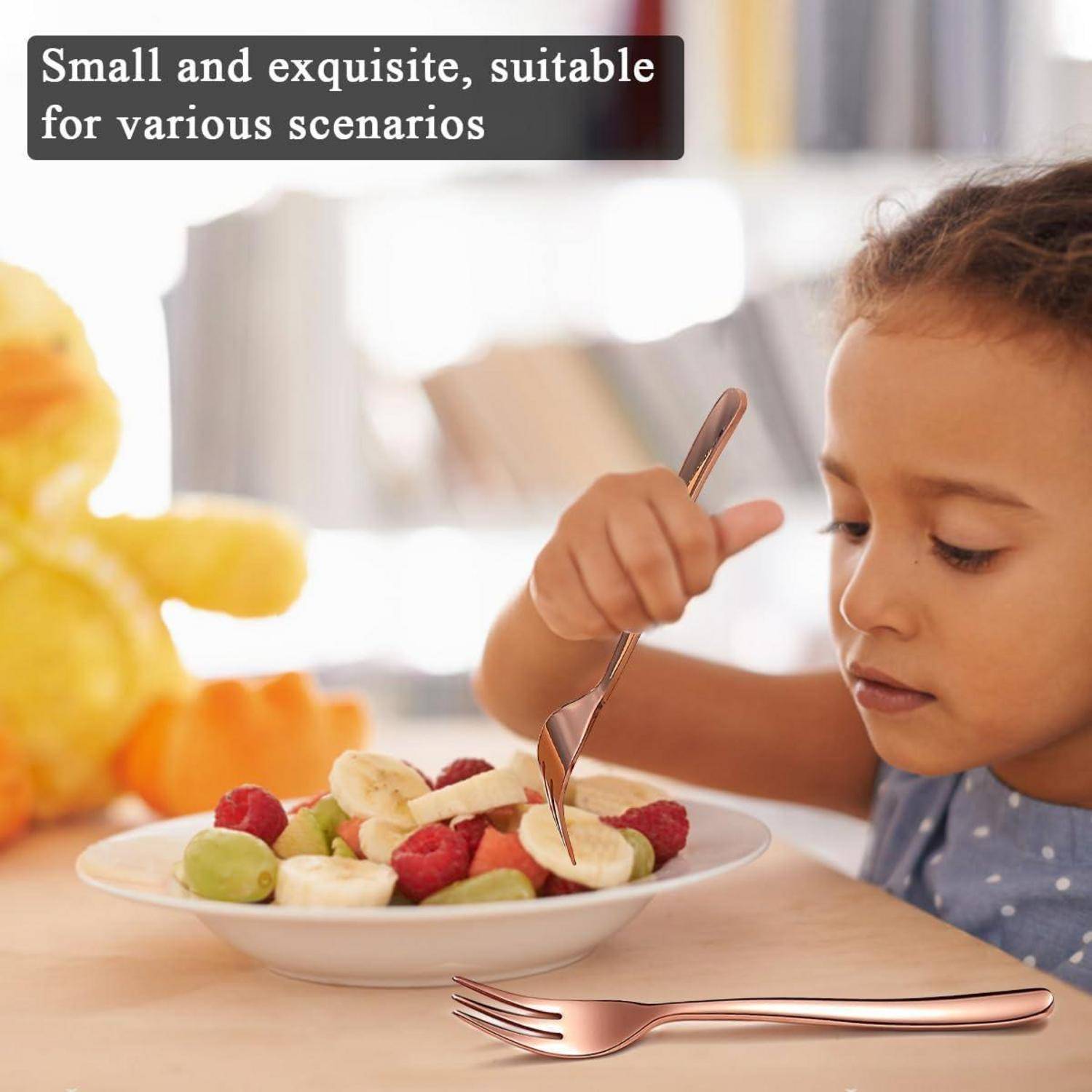 Ein Kind sitzt an einem Tisch und konzentriert sich darauf, einen Obstsalat mit einer Gabel zu essen. Ein Stofftier ist im Hintergrund unscharf.