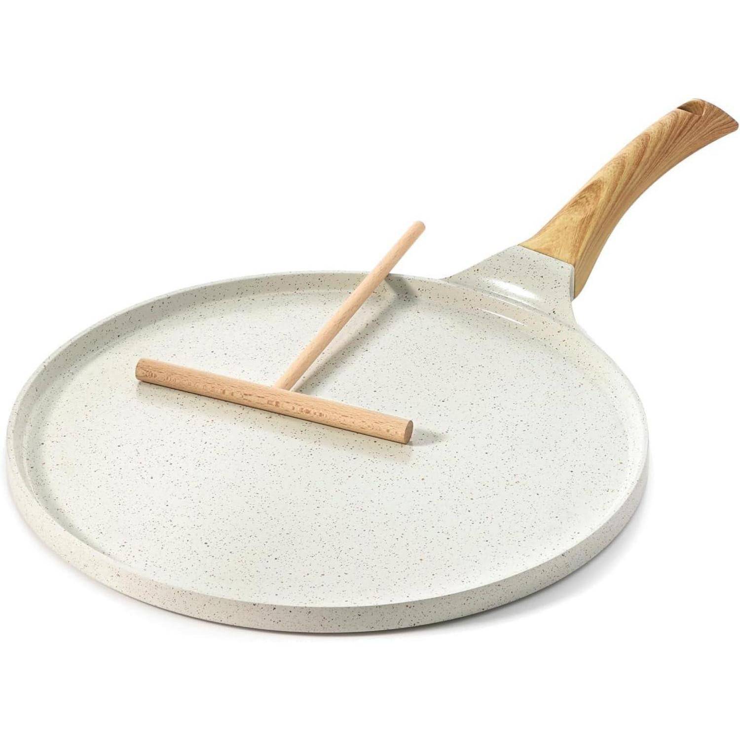 Eine weiße, gesprenkelte Crêpepfanne mit einem hellen Holzgriff und einem Holz-Crêpe-Verteiler.