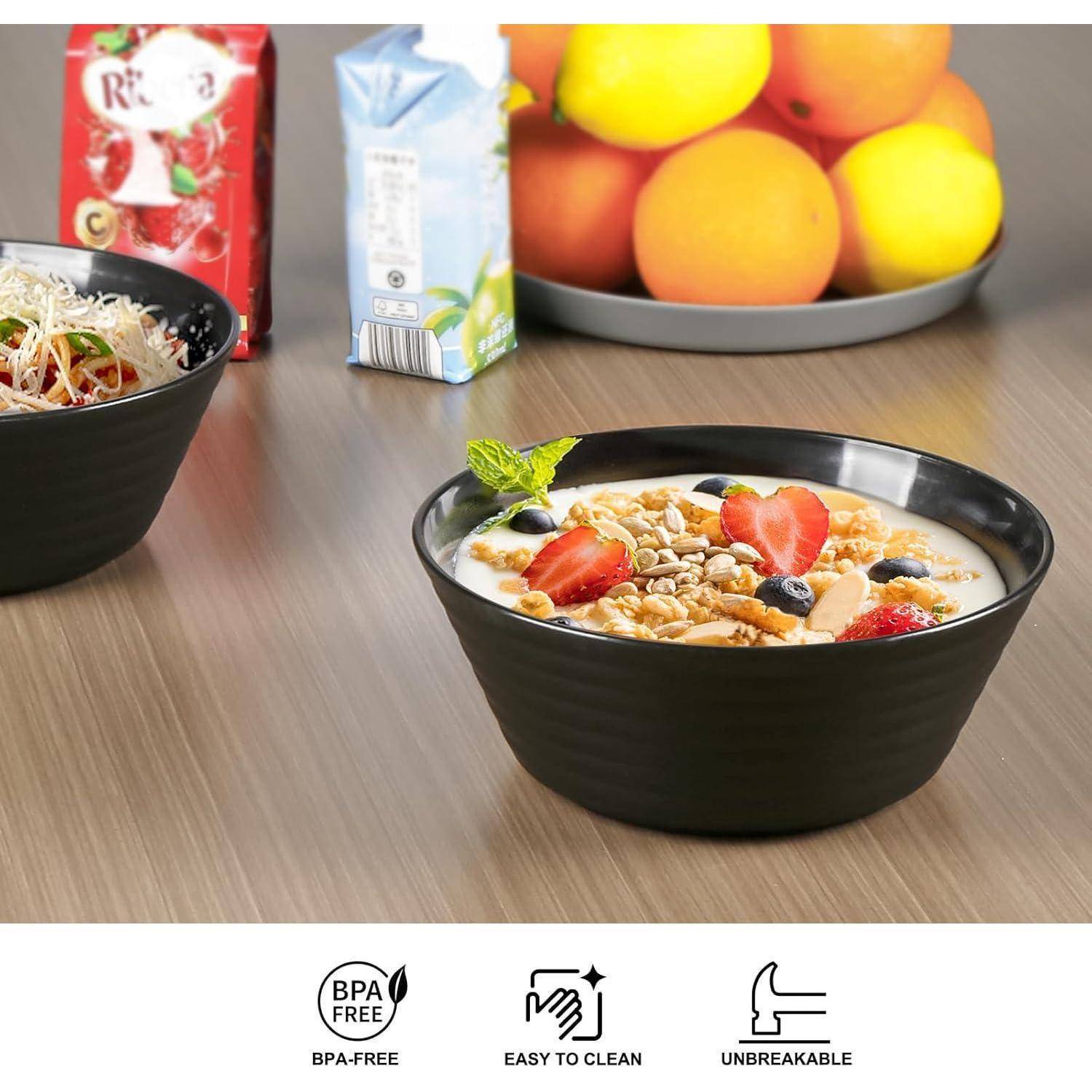 Eine Schüssel Müsli mit Erdbeeren und Nüssen steht auf einem Tisch. Dahinter befinden sich eine Saftpackung und eine Obstschale. Das Bild zeigt eine Mahlzeitensituation.