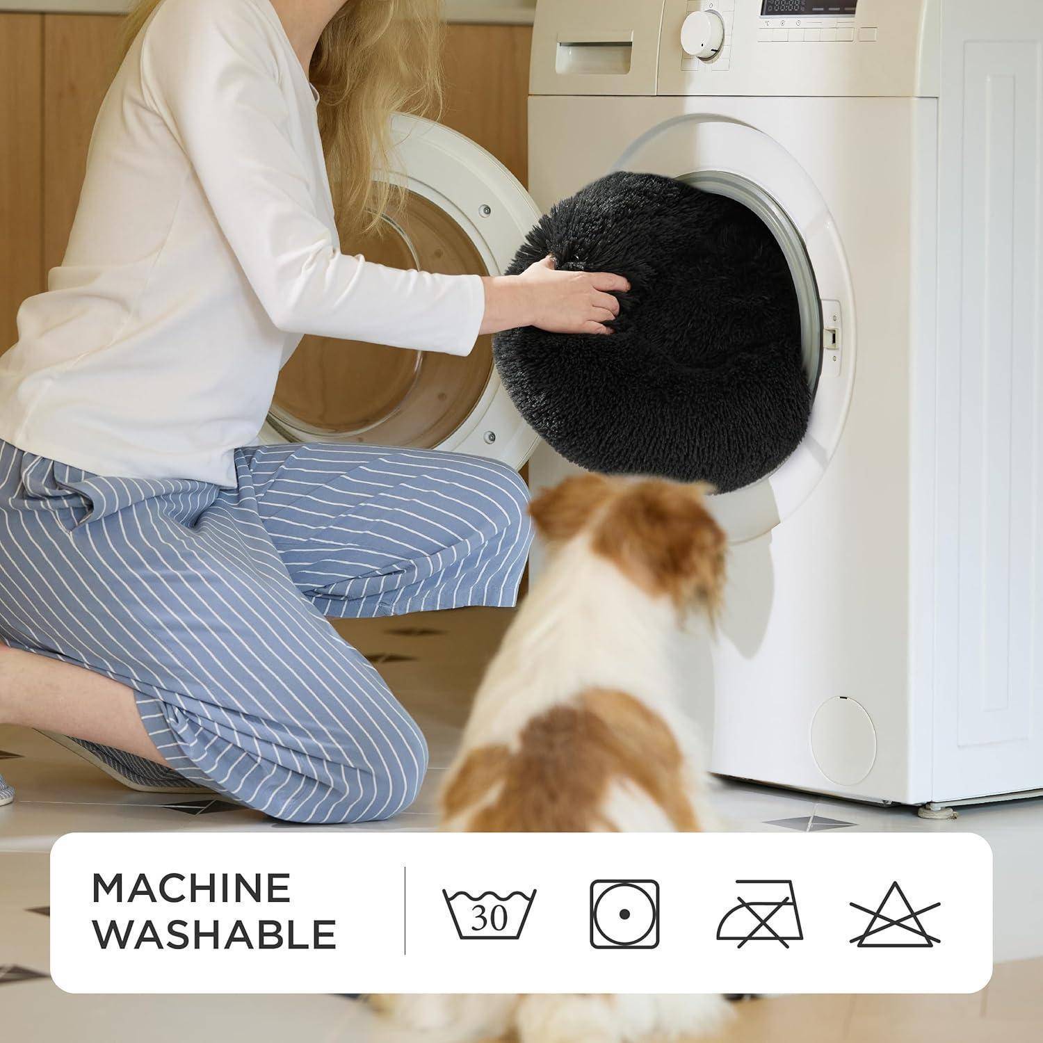 Eine Person legt ein schwarzes Kissen in eine Frontlader-Waschmaschine, während ein Hund zusieht. Icons unten zeigen „Maschinenwäsche