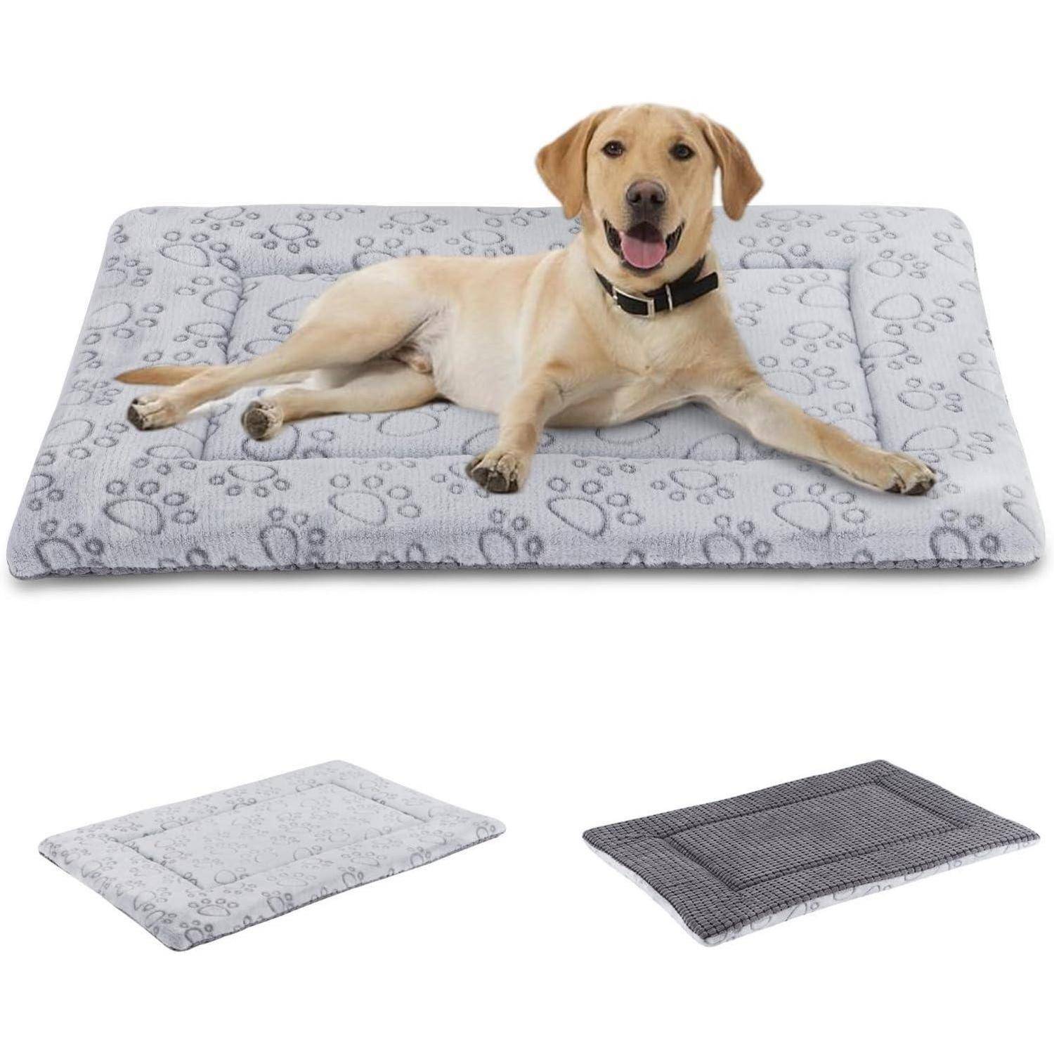 Ein glücklicher Hund liegt auf einer grauen Haustier-Matte mit Pfotenabdruckmustern. Das Bild zeigt auch zwei zusätzliche gefaltete Matten in verschiedenen Farben.
