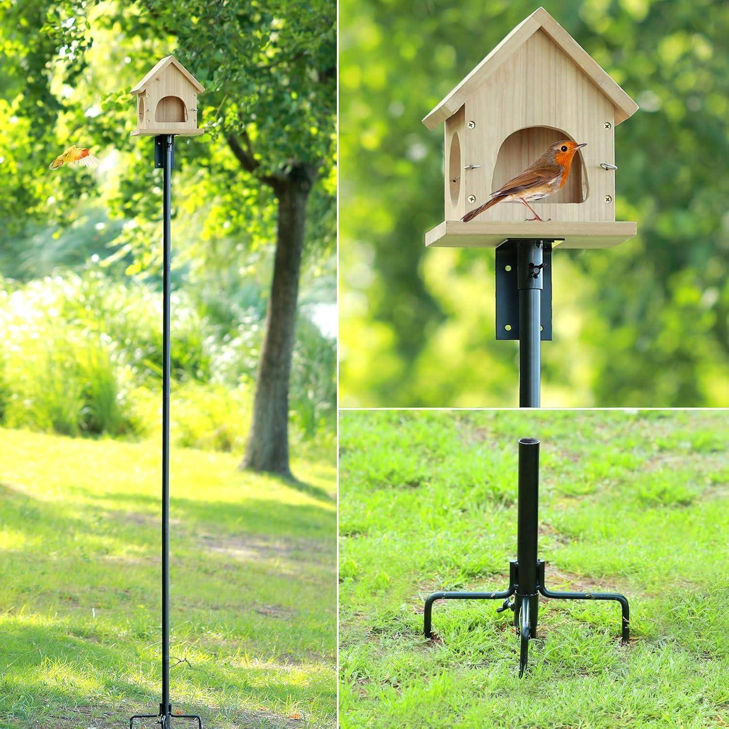 Ein hoher Vogelfutterspender auf einem Pfahl steht in einem grasbewachsenen Bereich, mit einem kleinen Vogel, der am Eingang des holzhaus-förmigen Futterhauses sitzt.