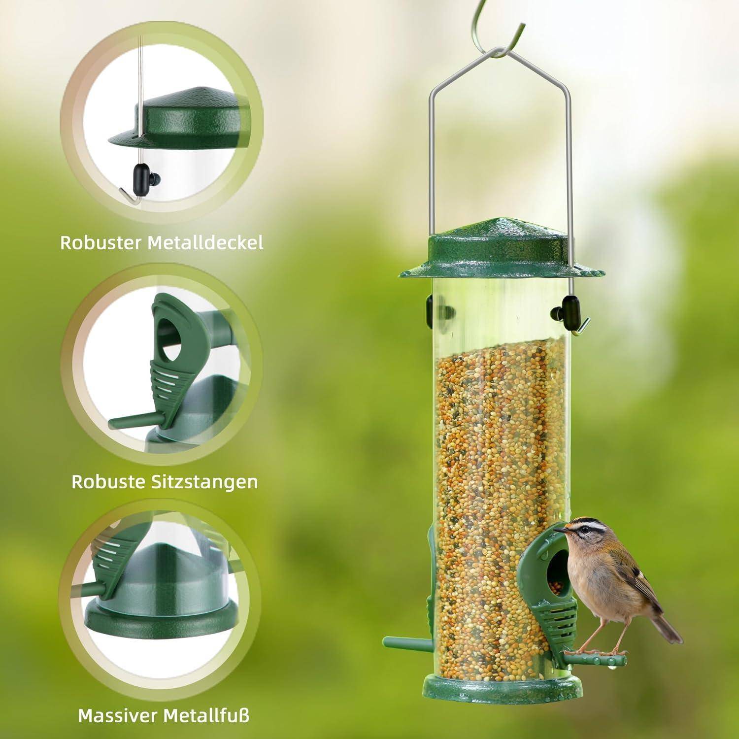 Ein Vogelfutterhäuschen mit einem Metalldeckel, Sitzstangen und einer Metalloberfläche, gefüllt mit Samen, hängt draußen. Ein kleiner Vogel sitzt darauf.