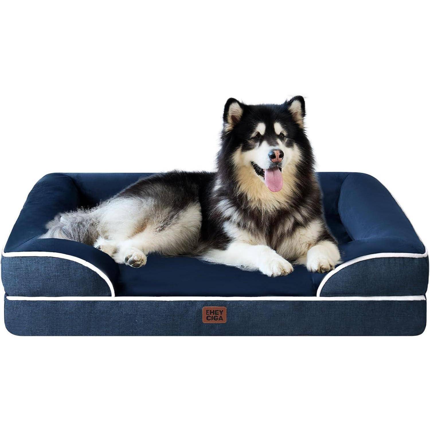 Ein großer, flauschiger Hund mit schwarz-weißem Fell liegt behaglich auf einem blauen orthopädischen Tierbett und sieht zufrieden aus, wobei seine Zunge herausgestreckt ist.