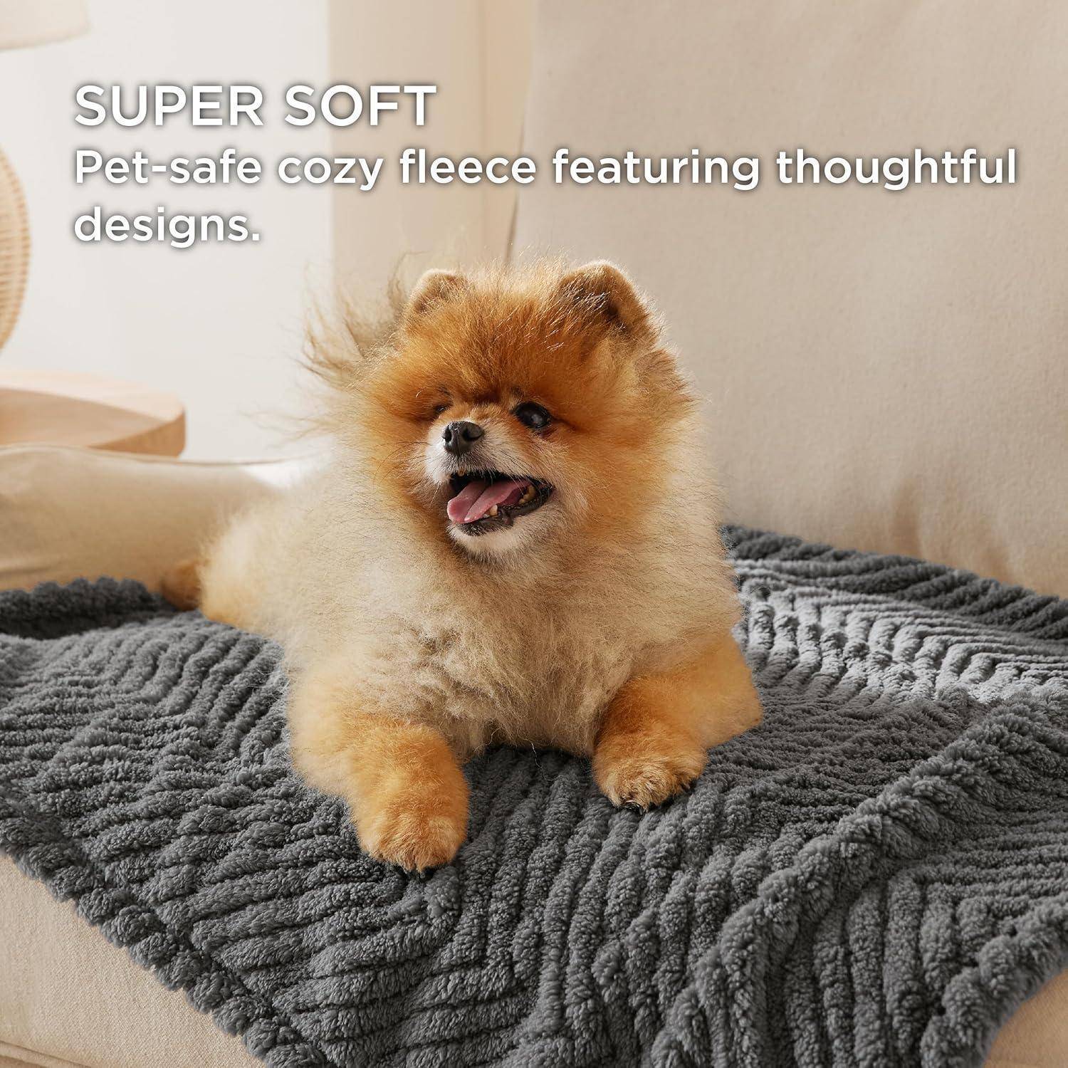 Ein flauschiger Hund liegt auf einer dunkelgrauen Fleece-Decke auf einem beigen Sofa. Text lautet: „SUPER WEICH Haustierfreundliche gemütliche Fleece-Decke mit durchdachten Designs.