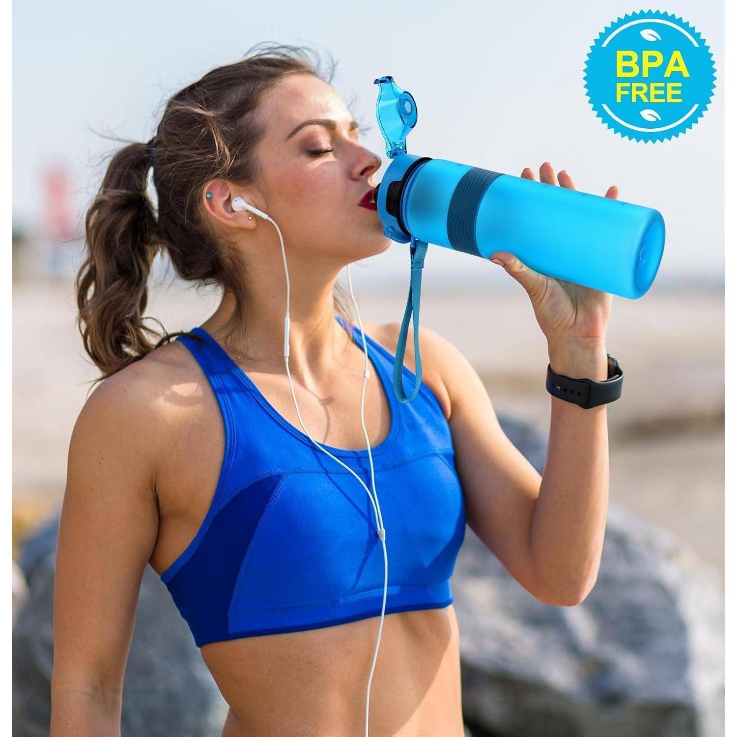 Frau in blauer Sportkleidung trinkt Wasser aus einer BPA-freien Flasche, trägt Kopfhörer und eine Smartwatch, im Freien.