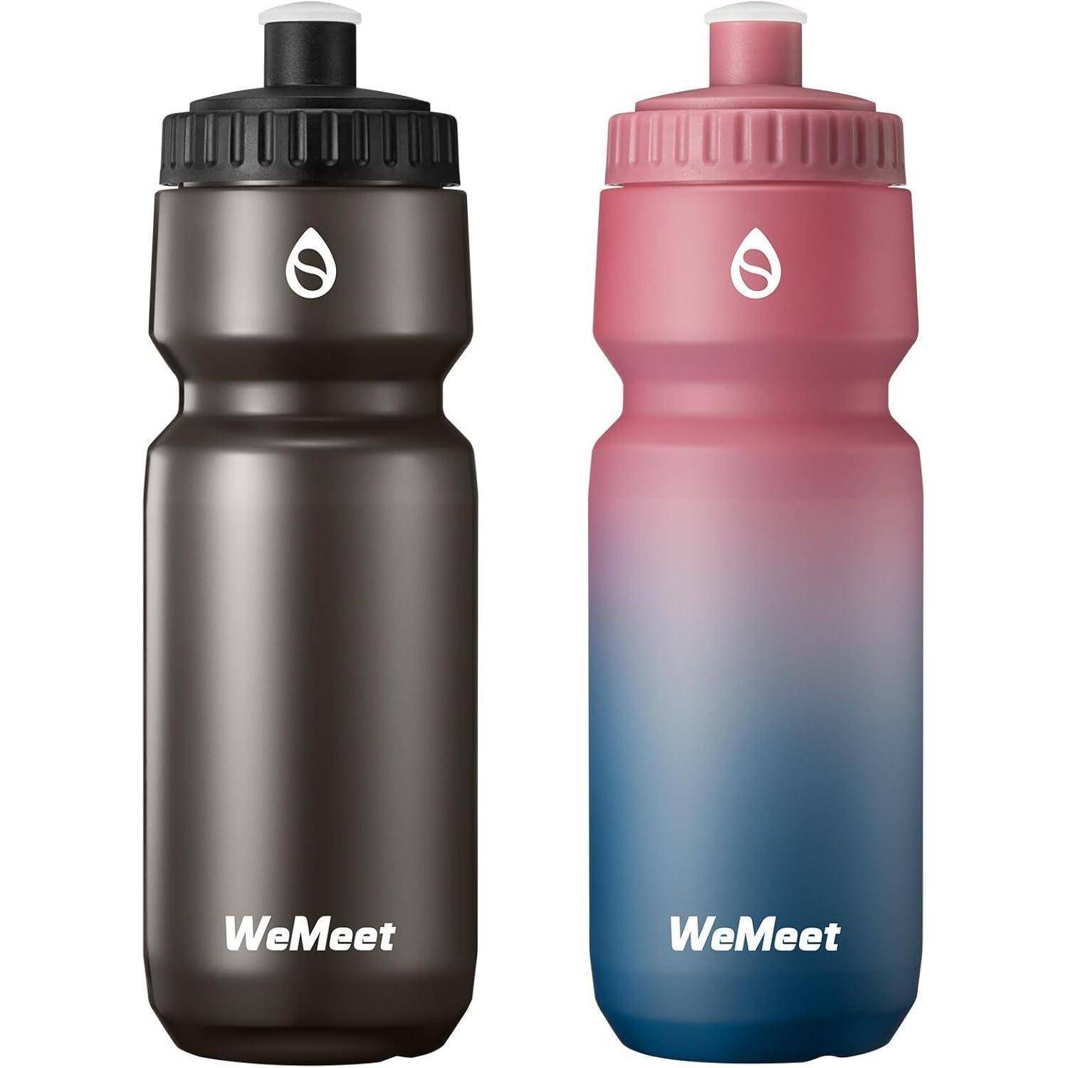 Zwei 'WeMeet' Wasserflaschen: eine schwarz, eine in Verlaufsfarben von Rosa zu Blau, beide mit Tropfen-Logo und Schraubdeckel.