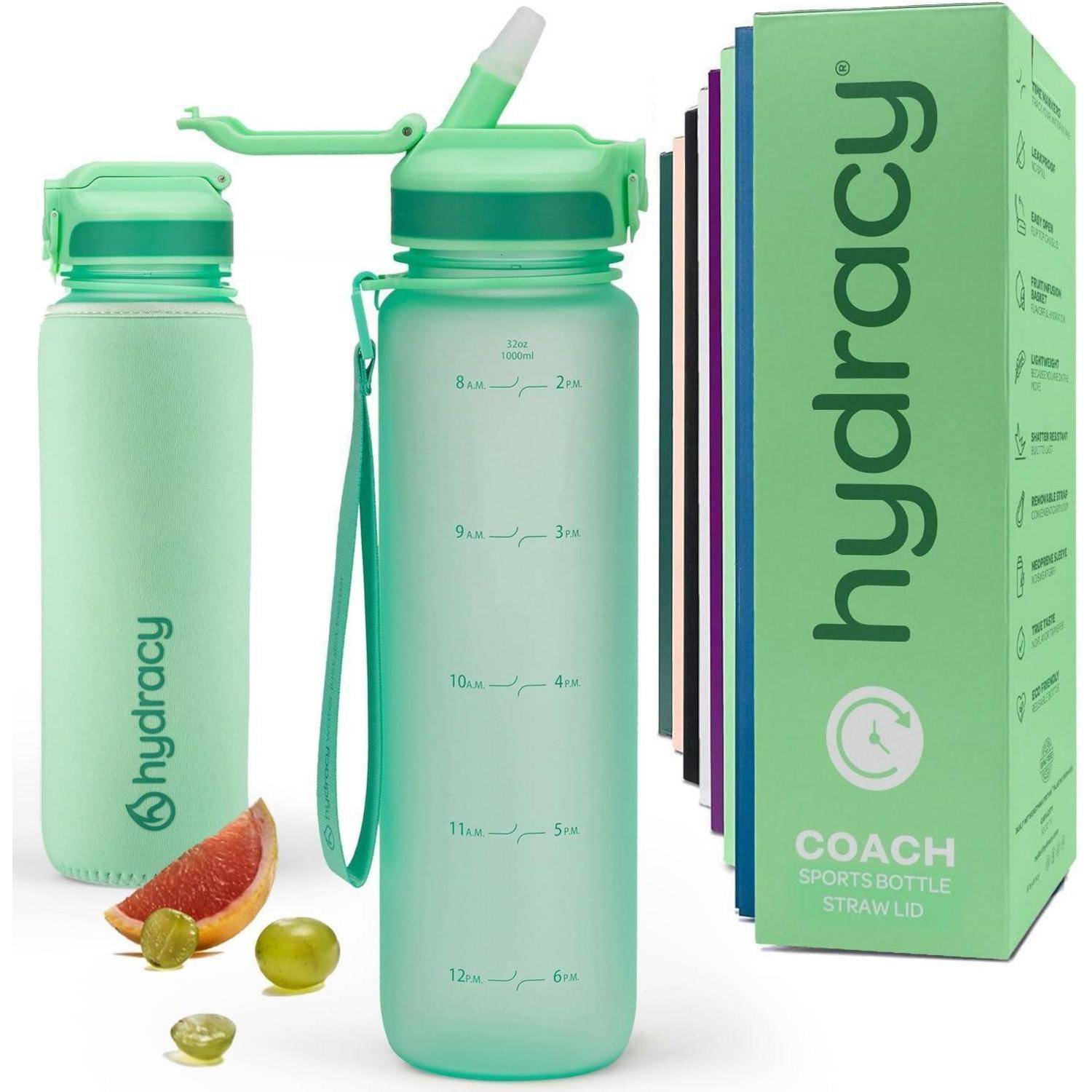Zwei grüne Hydracy Sportflaschen mit Messmarkierungen und Deckel mit Strohhalm. Eine Zitrusecke und Trauben liegen in der Nähe. Die Verpackung wird ebenfalls gezeigt.
