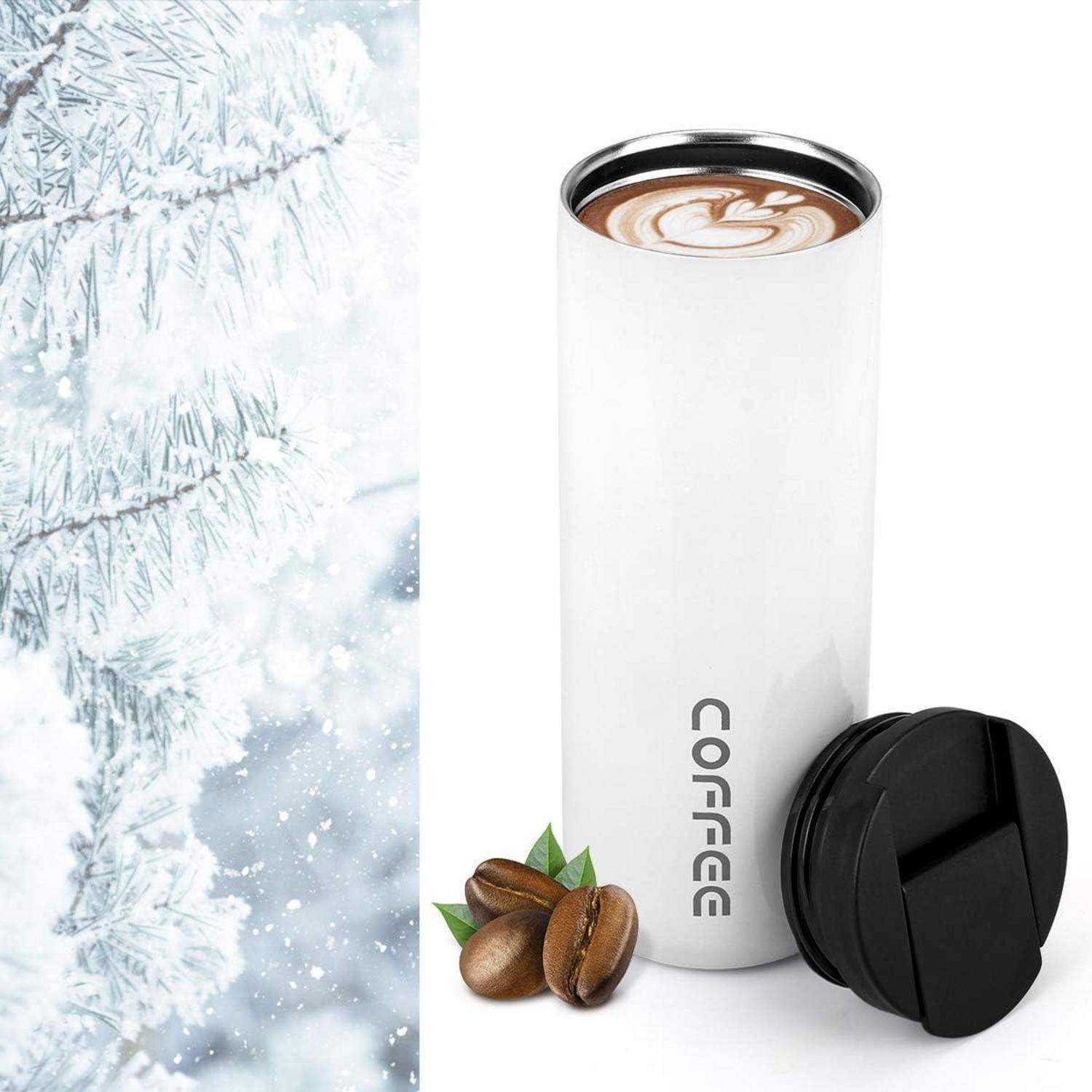 Thermobecher mit Latte-Art, neben Kaffeebohnen und einem schneebedeckten Kiefernzweig, der ein Gefühl von Wärme in einer Winterlandschaft vermittelt.
