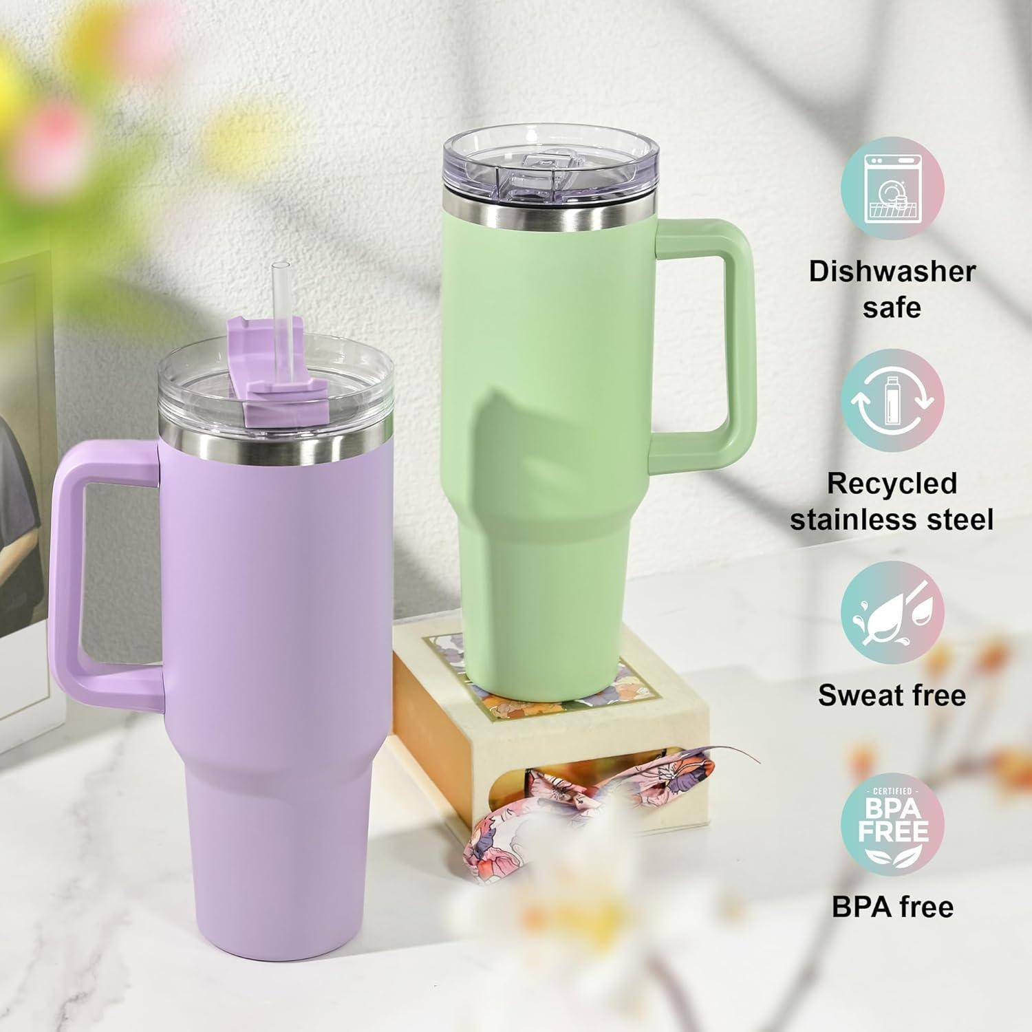 Zwei isolierte Becher, einer lila und einer grün, mit Henkeln auf einem Tisch. Symbole daneben zeigen ‚Spülmaschinenfest', ‚Recycelter Edelstahl', ‚Schweißfrei' und ‚BPA-frei'.