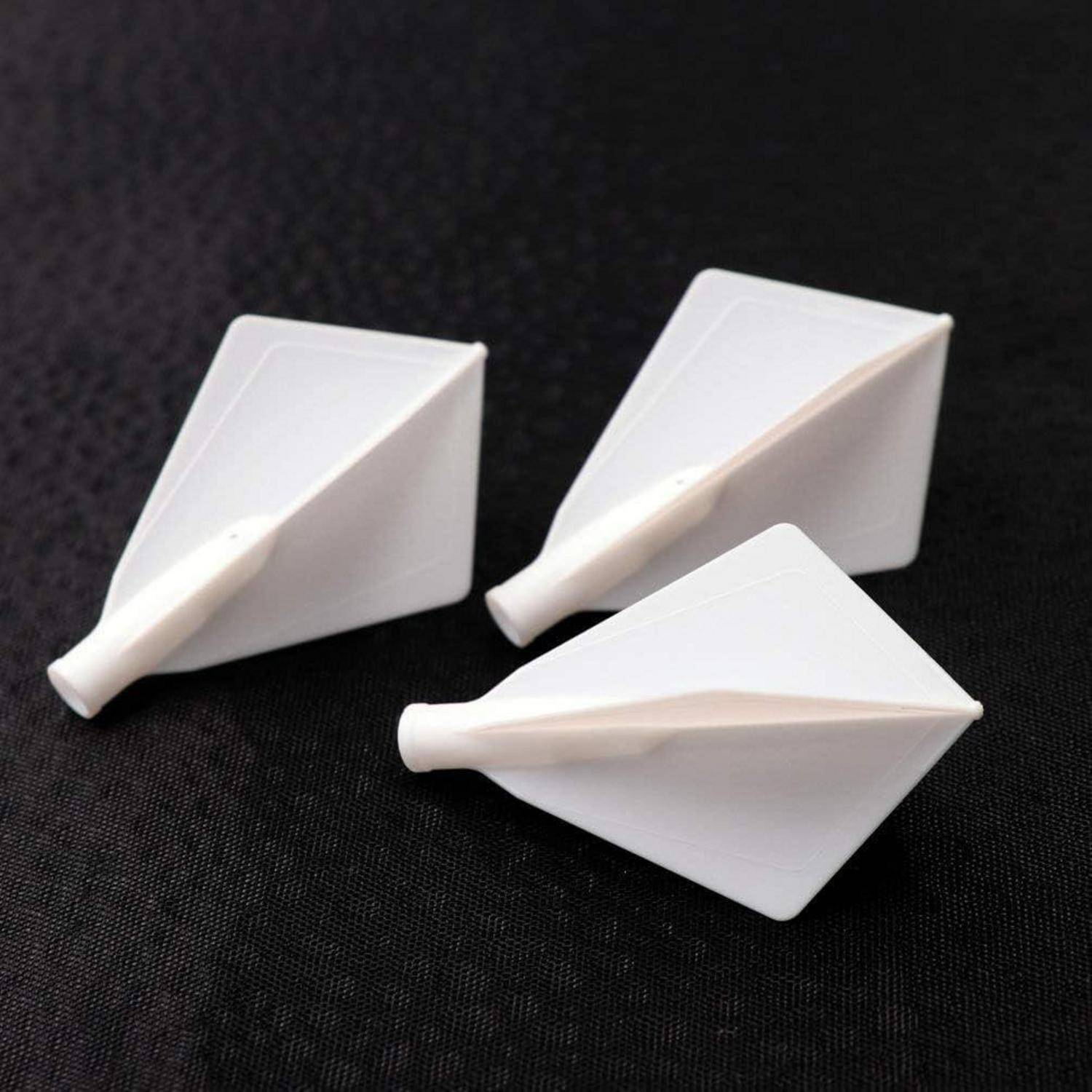 Drei weiße Dartflights auf einer strukturierten schwarzen Oberfläche, dicht nebeneinander angeordnet, wodurch ihre kantige Form und glatte Textur betont werden.
