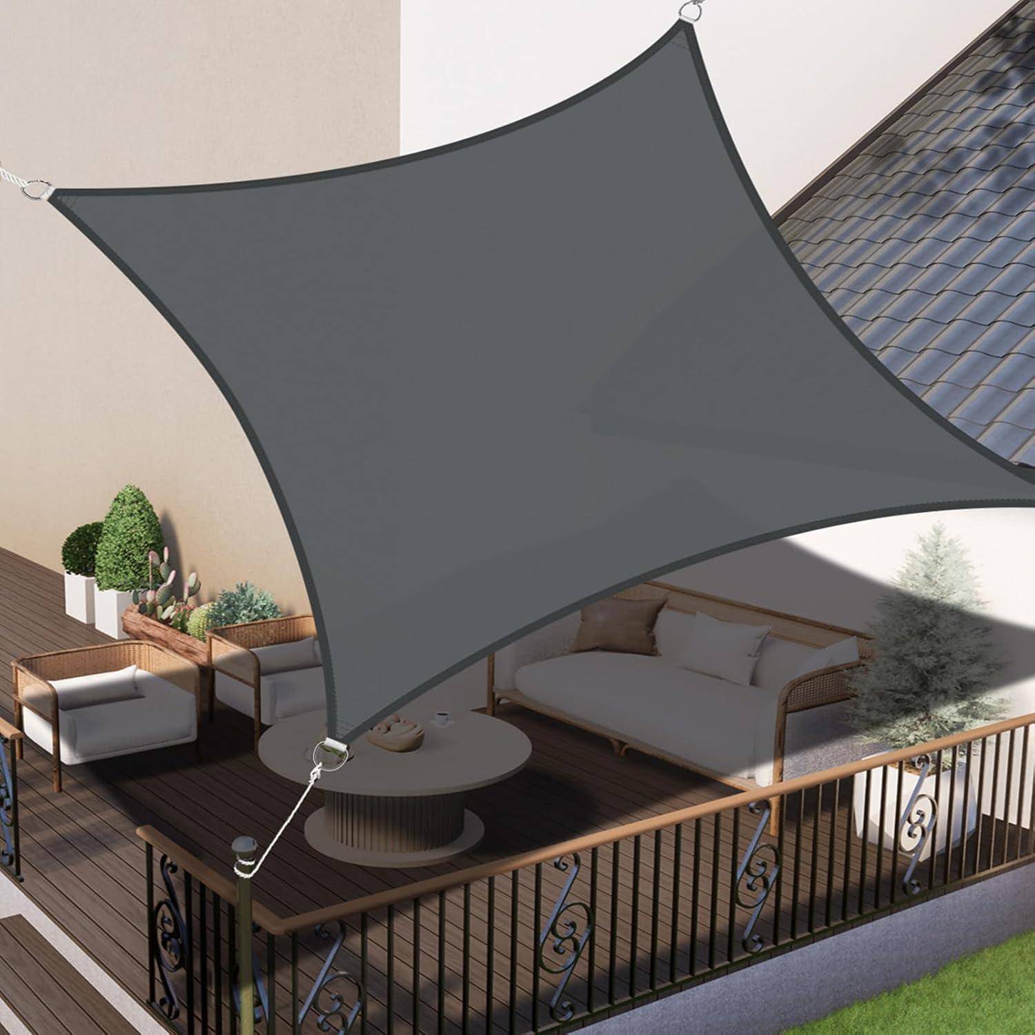 Eine überdachte Terrasse im Freien präsentiert sich mit einem dreieckigen grauen Sonnensegel, Rattanmöbeln und Kübelpflanzen und bietet einen modernen und entspannenden Raum.