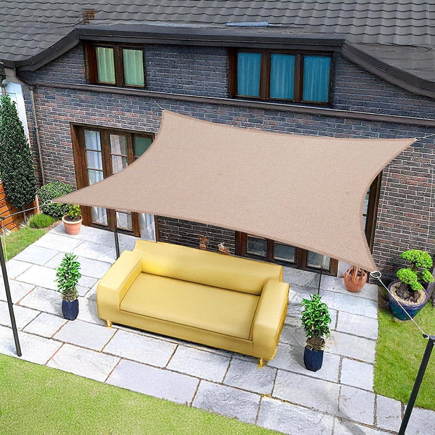 Ein beiger Sonnenschirm bedeckt ein gelbes Sofa auf einer Terrasse mit Topfpflanzen, vor einem Backsteinhaus mit großen Fenstern.