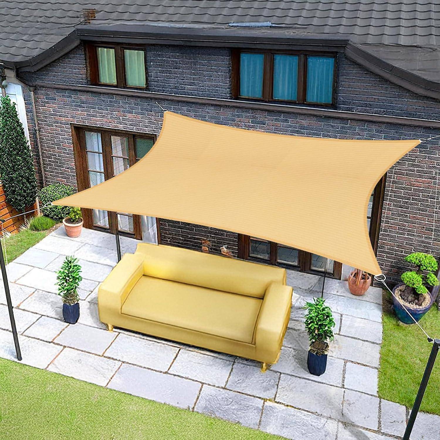 Eine Terrasse mit einem beigen Sonnensegel, die eine gelbe Couch beschattet, umgeben von Kübelpflanzen, in der Nähe eines großen Backsteingebäudes mit großen Fenstern.
