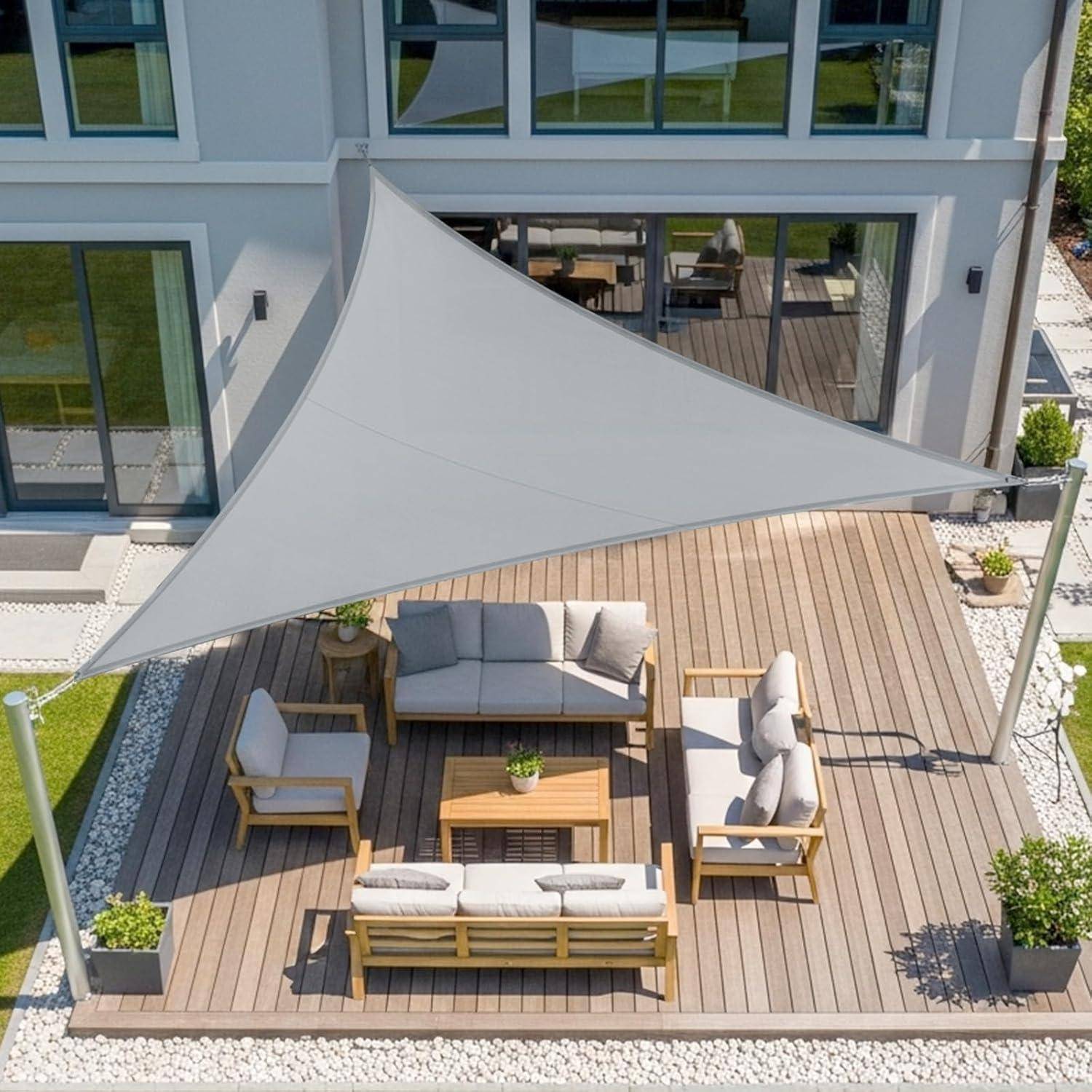 Luftaufnahme einer modernen Außenterrasse mit gepolsterten Sitzmöbeln, einem Holztisch und einem großen dreieckigen Sonnensegel, alles auf einer Holzterrasse.