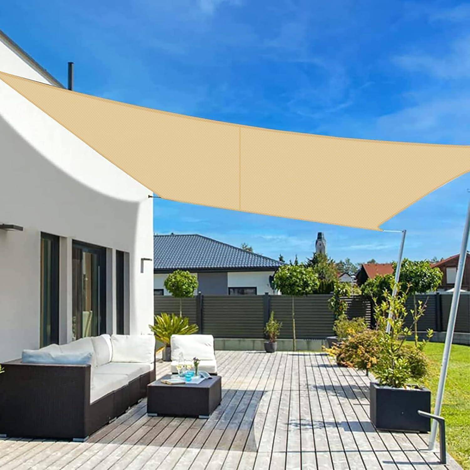 Eine moderne Terrasse mit einer Holzterrasse, weißem Sofa, Tisch, Topfpflanzen und einem beigen Sonnenschutz. Häuser und blauer Himmel sind im Hintergrund sichtbar.