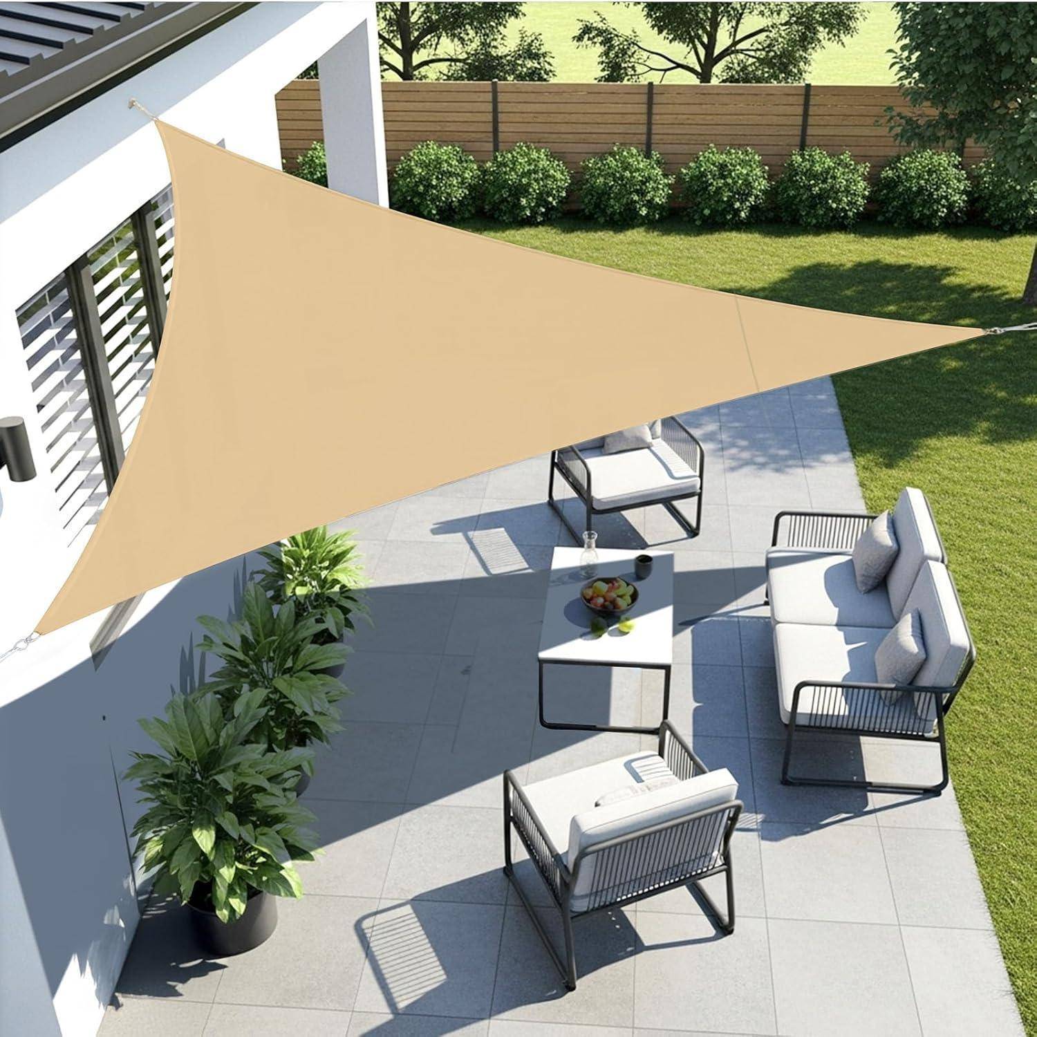 Eine Terrasse mit moderner Outdoormöbeln an einem sonnigen Tag, beschattet von einem großen dreieckigen beigen Segel, das an einem Gebäude befestigt ist.