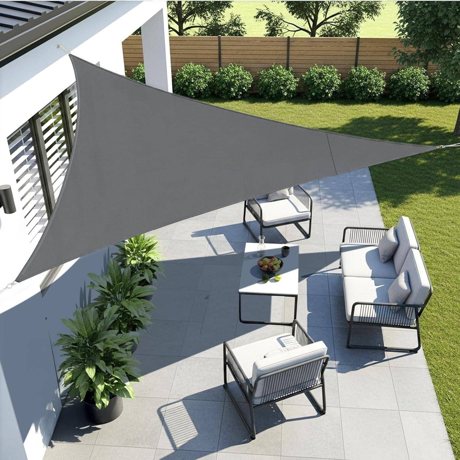Terrasse mit moderner Outdoor-Möblierung und einem großen grauen dreieckigen Sonnenschutz, der den Bereich teilweise vor der Sonne schützt.