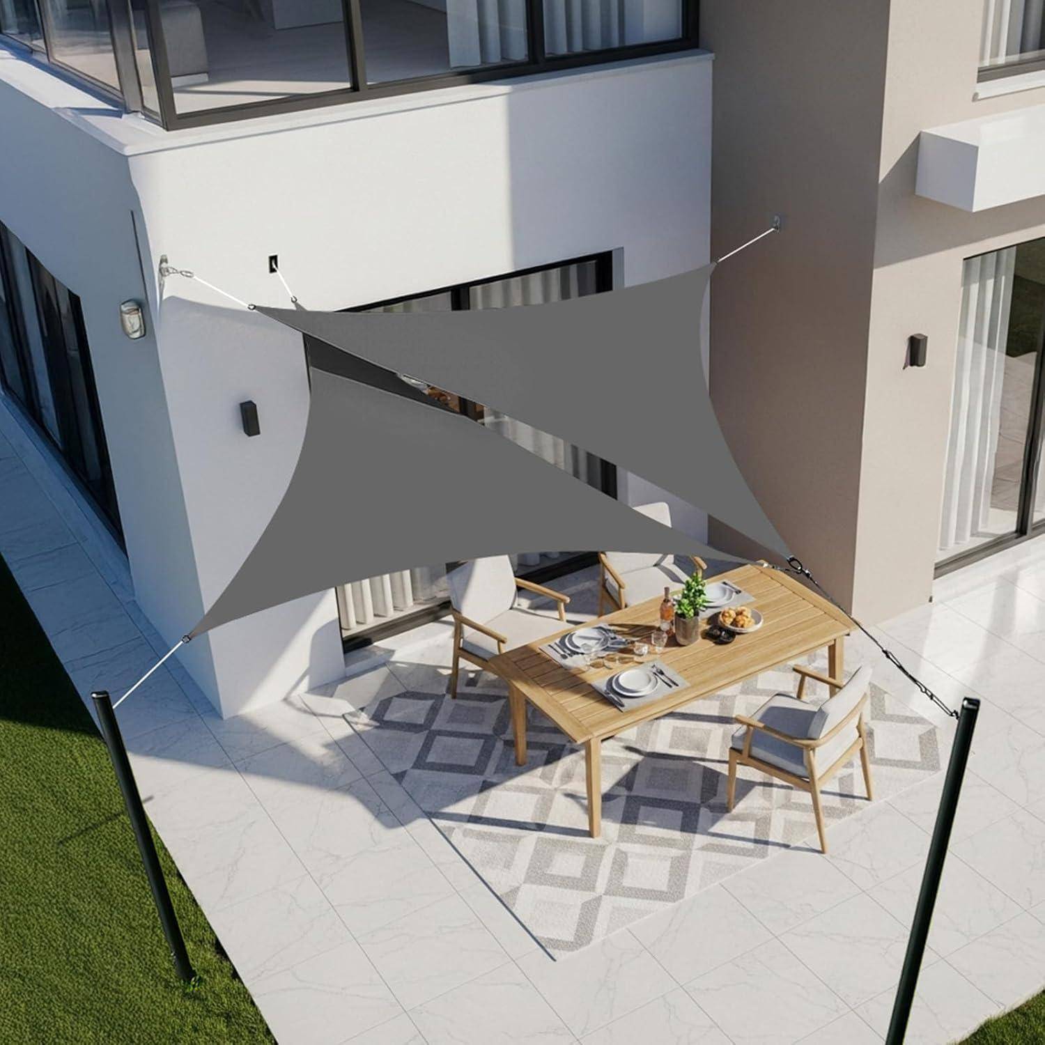 Eine Terrasse mit einem Holz-Esstisch und sechs Stühlen unter einem dreieckigen grauen Sonnensegel, das an einem Haus befestigt ist und einen schattigen Außenbereich schafft.