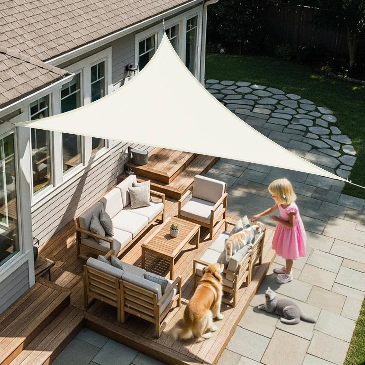 Ein Mädchen in einem rosa Kleid streichelt einen Hund auf einer Holzterrasse mit Sitzgelegenheiten und einem Sonnensegel, das an einem Haus befestigt ist, in einem Hinterhof mit Steinstufen.