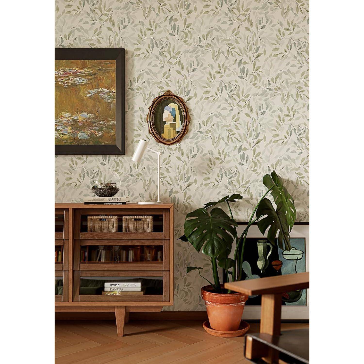 Ein gemütliches Wohnzimmer mit blättrigem Tapetenmuster, einer Holzkonsole mit Büchern, einer Zimmerpflanze und zwei gerahmten Kunstwerken, eines größer und eines oval.