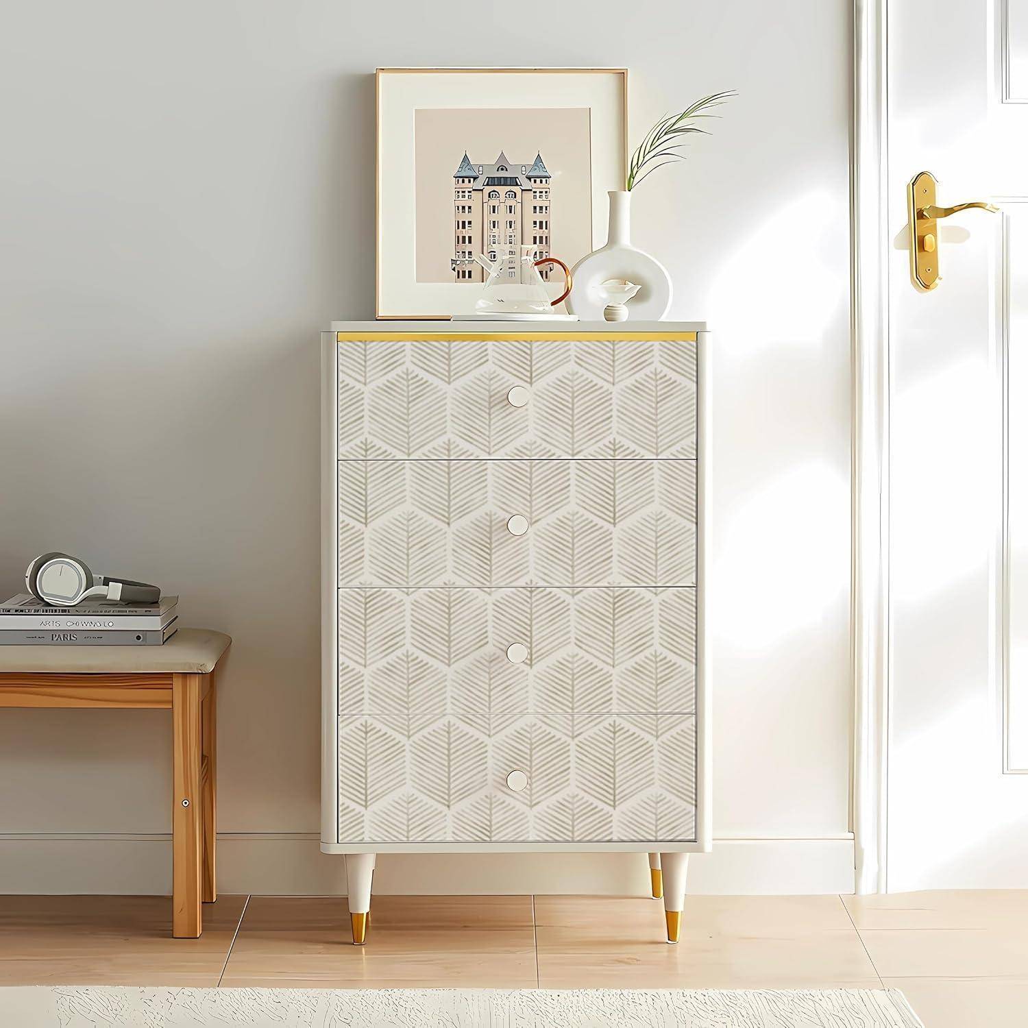 Ein hoher Schrank mit geometrisch gemusterten Schubladen steht neben einer geschlossenen Holztür. Ein gerahmtes Bild und eine Pflanze stehen auf der Oberfläche.