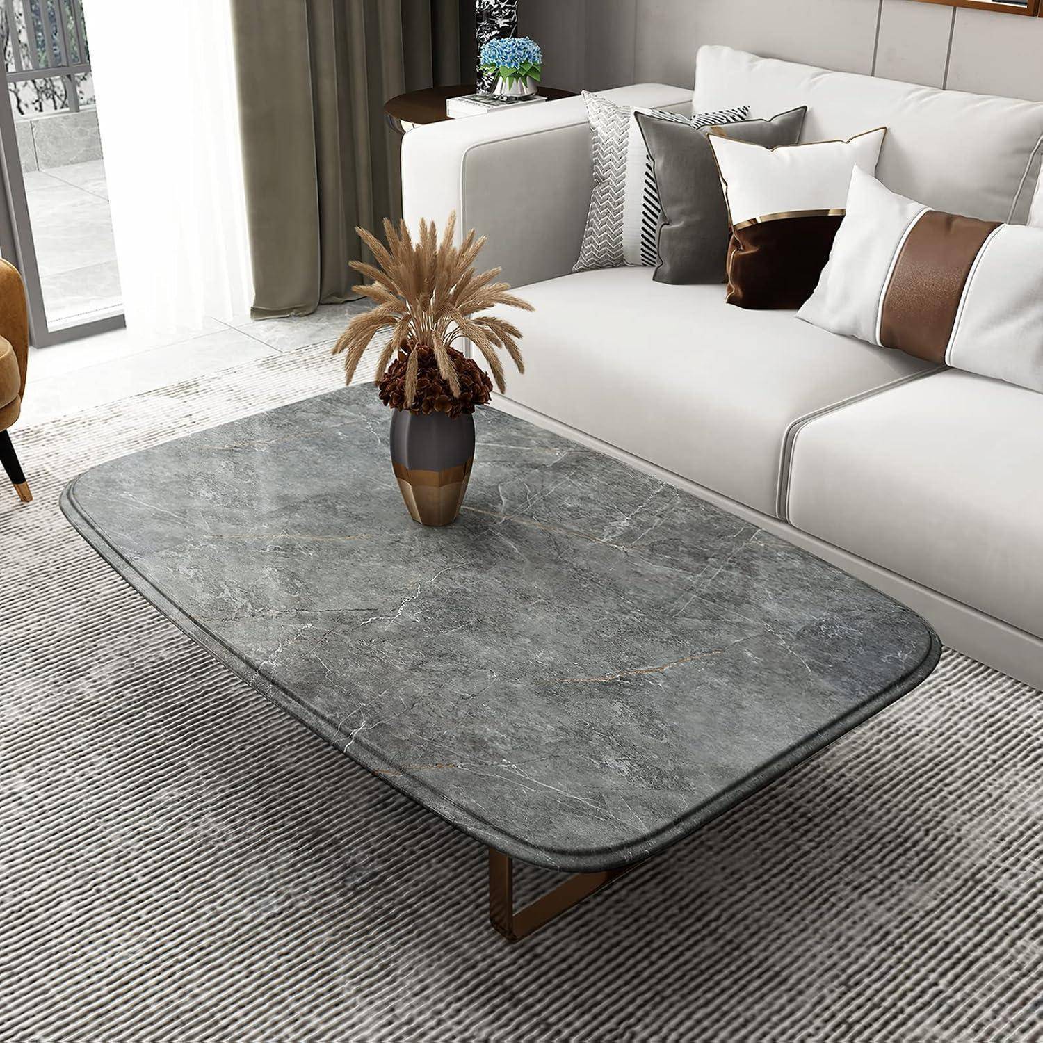Ein modernes Wohnzimmer mit einem grauen Marmor-Couchtisch, braunen und weißen Kissen auf einem weißen Sofa und einer Pflanze auf dem Tisch.