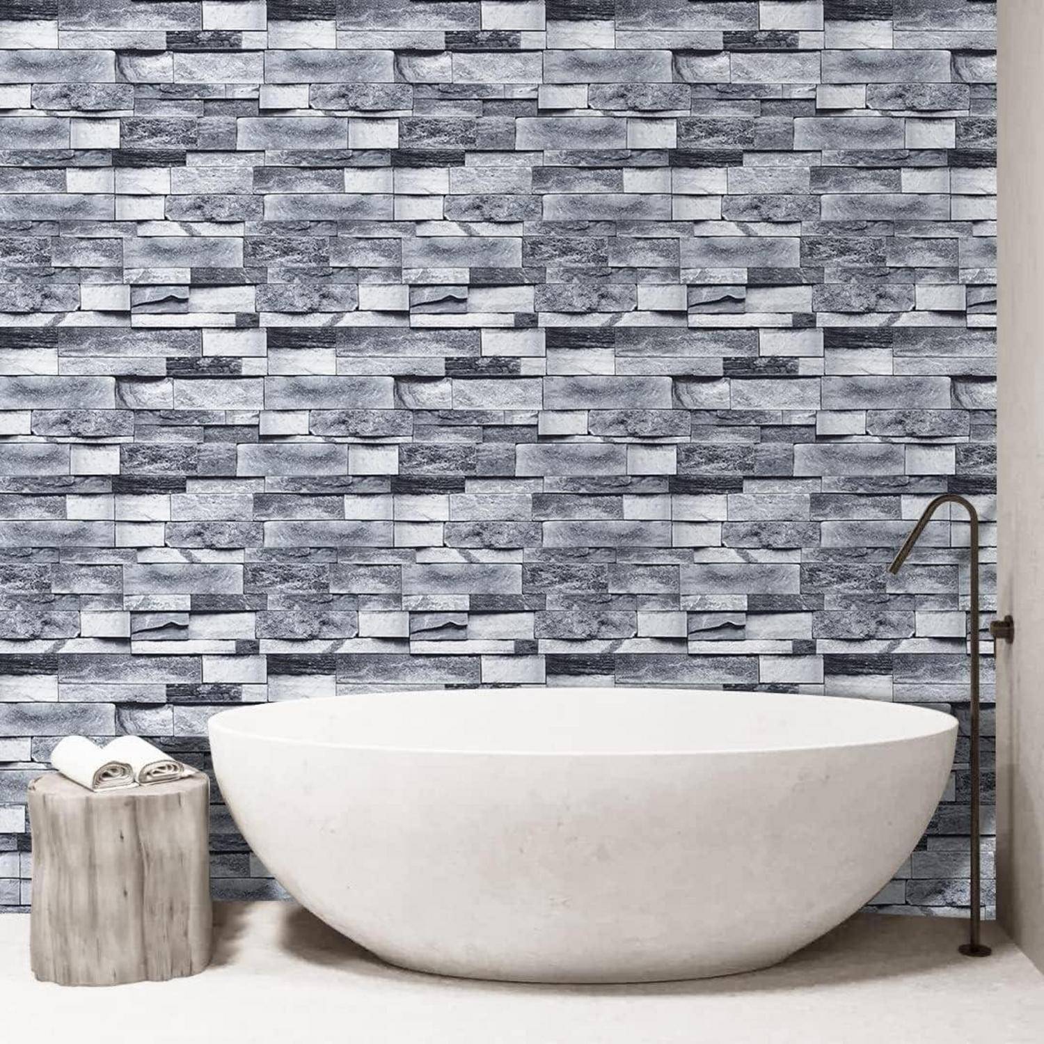 Modernes Badezimmer mit einer großen, weißen ovalen Badewanne, die vor einer strukturierten grauen Natursteinfliesen-Wand steht und einen eleganten, minimalistischen Designstil schafft.