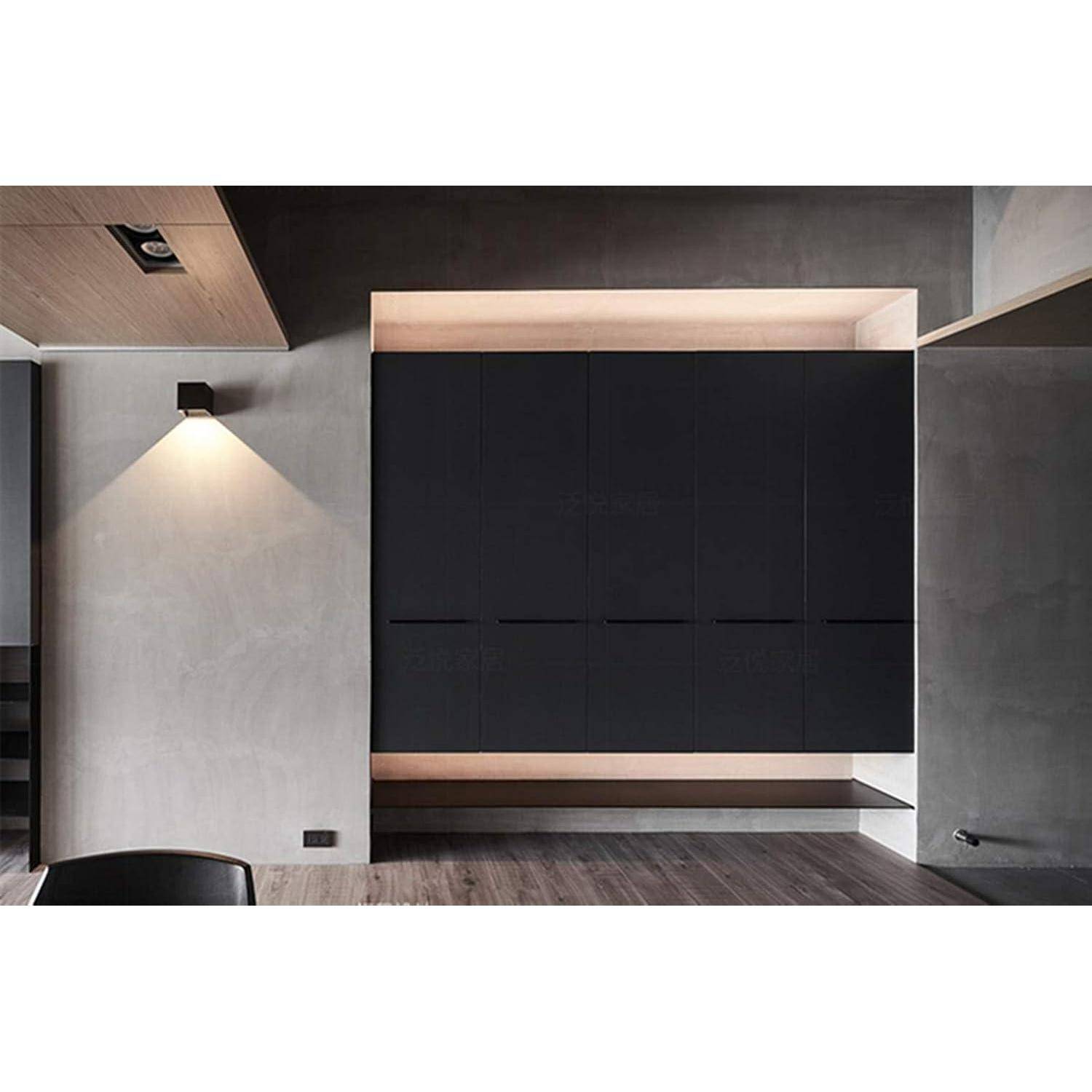 Ein modernes, minimalistisches Interieur mit einem großen, dunklen Schrank, der an einer grauen Wand montiert ist, mit Ambientebeleuchtung, die weiche Schatten wirft.