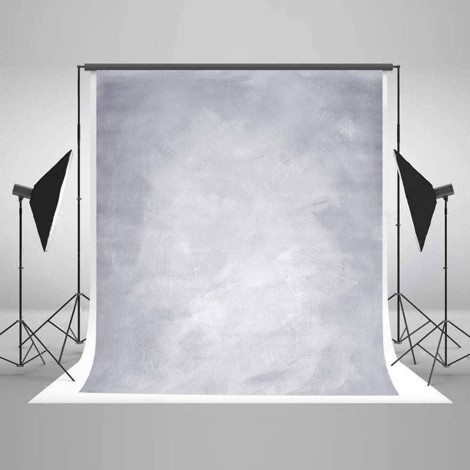 Ein Fotostudio-Setup mit einem schlichten grauen Hintergrund, zwei Studiolampen auf Ständern und einem glatten reflektierenden Boden, bereit für eine Fotosession.