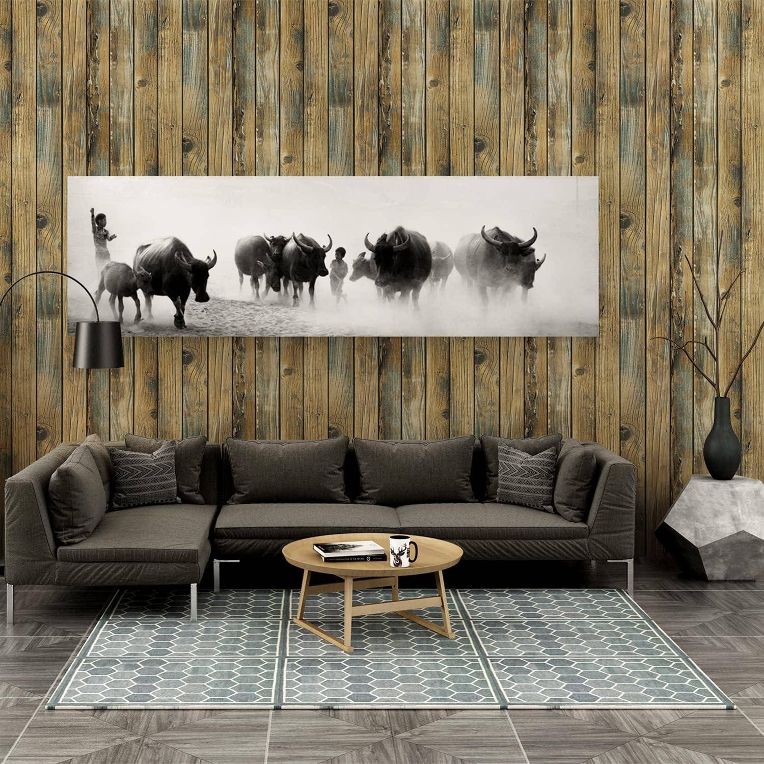 Ein modernes Wohnzimmer mit einem grauen Sofa, einem Holzcouchtisch und einem gemusterten Teppich. Ein großes Schwarz-Weiß-Foto von Wasserbüffeln hängt an der Wand.