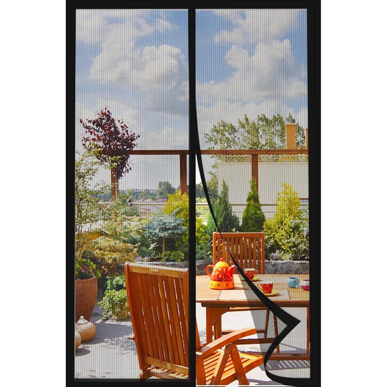 Eine Terrasse mit Holzmöbeln blickt auf einen Garten mit Bäumen und Sträuchern unter einem bewölkten Himmel. Eine Glastür rahmt die Außenansicht ein.