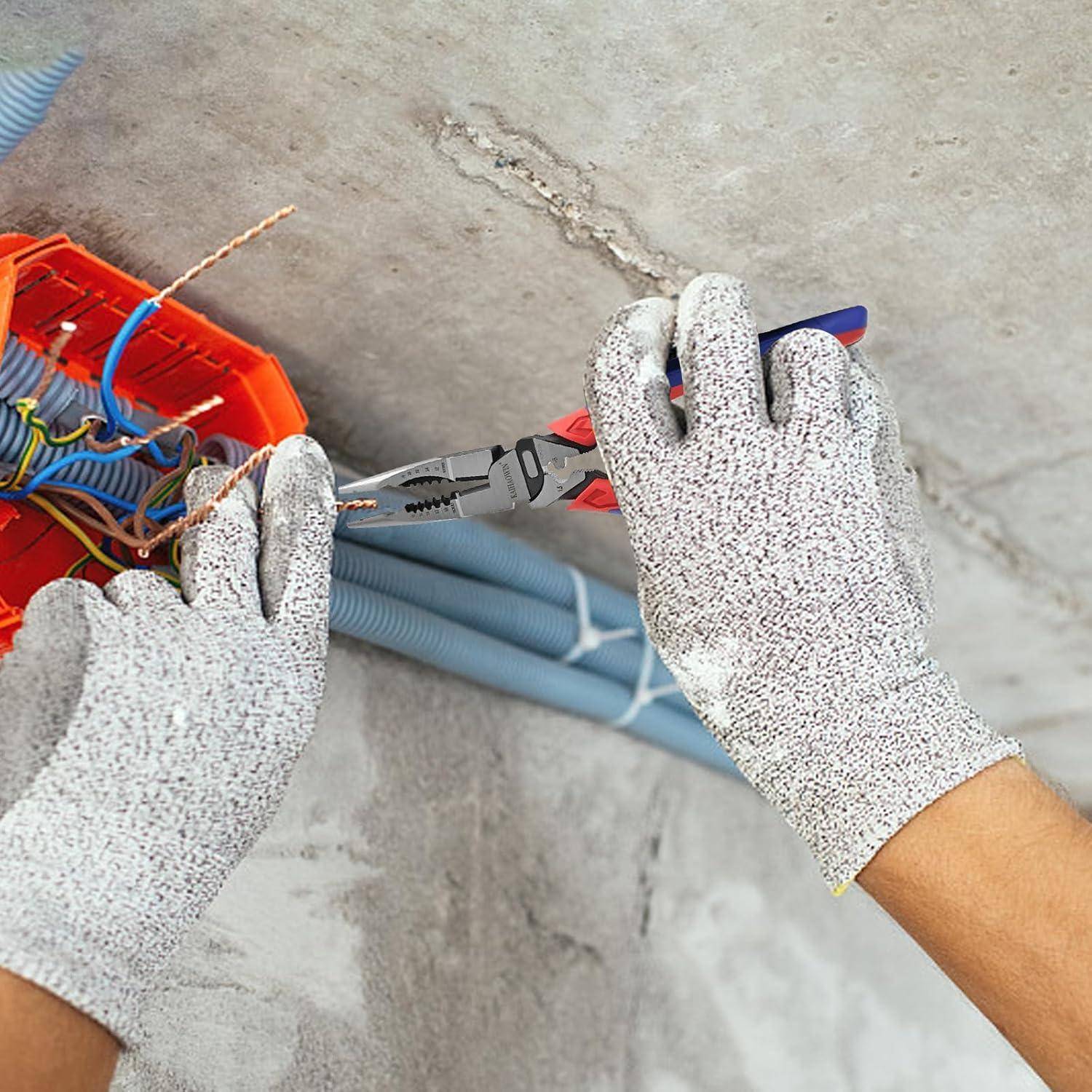 Ein Elektriker mit Handschuhen benutzt Zangen, um Kabel aus einer Elektroverteilerdose an einer Betonwand auszustrippen.