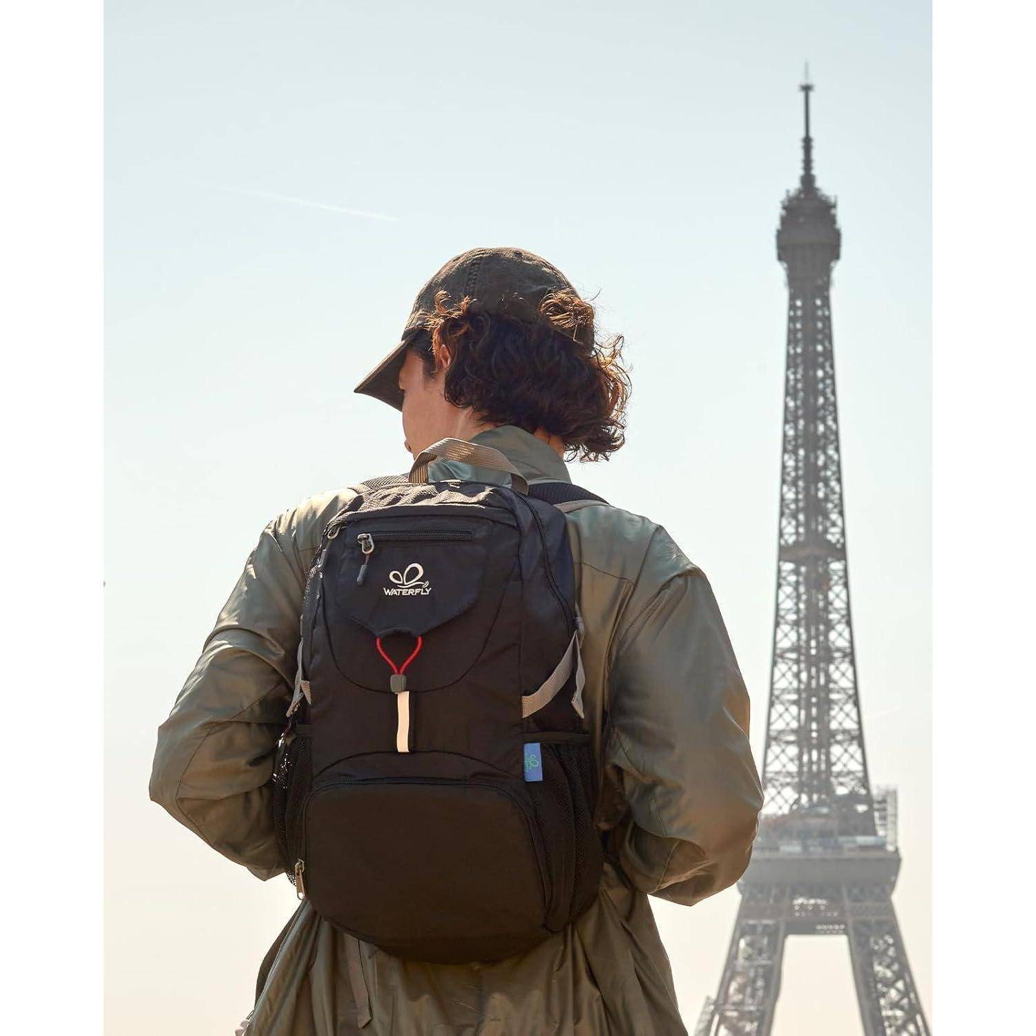 Eine Person mit Hut und Rucksack steht vor dem Eiffelturm bei Tageslicht und deutet auf eine Reise in Paris hin.