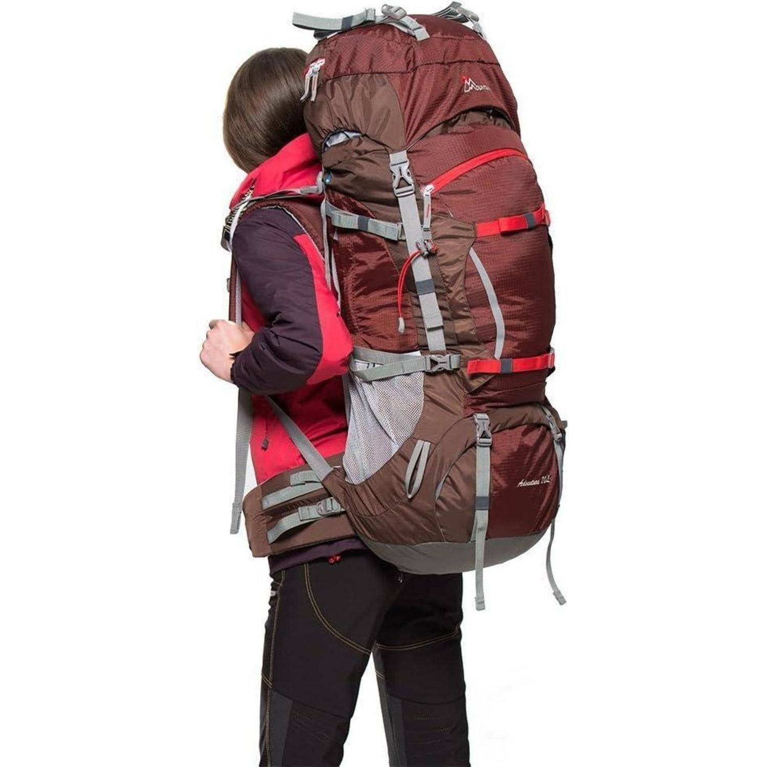 Eine Person mit einem großen rot-braunen Wanderrucksack, die eine rote Jacke und schwarze Hosen trägt, seitlich gedreht.