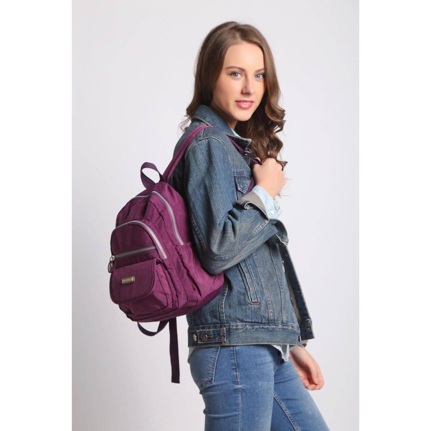 Eine Person mit einer Jeansjacke und Jeans steht mit einem lila Rucksack und blickt in die Kamera.