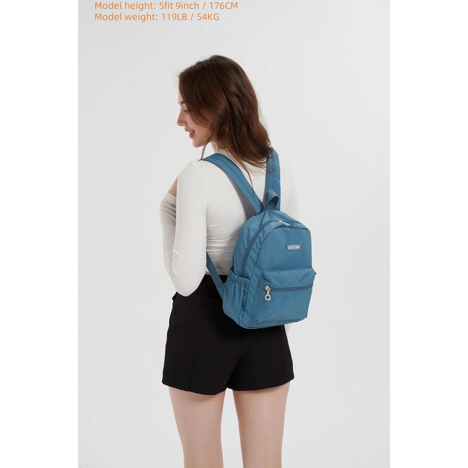 Eine Frau mit einem weißen Langarmshirt, schwarzen Shorts und einem blauen Rucksack steht vor einem einfarbigen Hintergrund und blickt zur Seite.