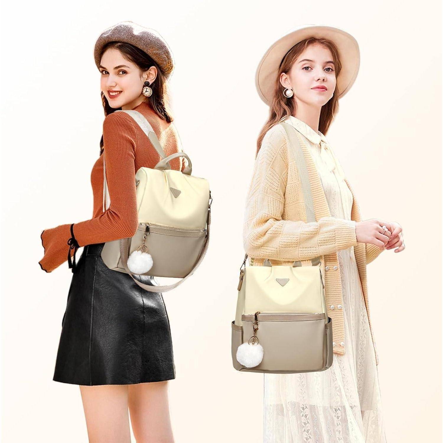 Zwei Frauen stehen Rücken an Rücken, beide tragen stilvolle Rucksäcke mit Pompom-Schlüsselanhängern. Sie tragen Herbstoutfits, eine im Rock, die andere im Kleid.