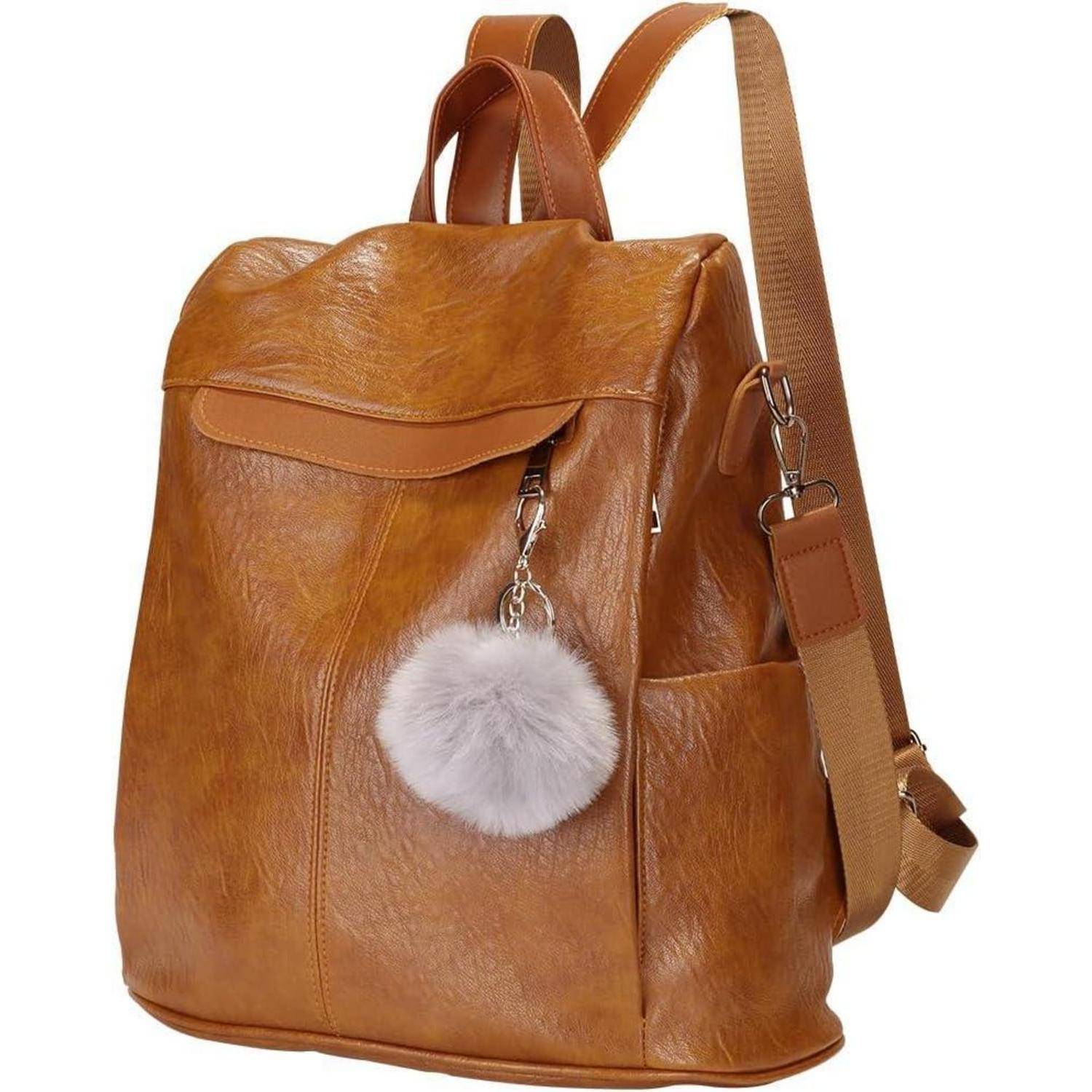 Brauner Lederrucksack mit einer Reißverschlusstasche vorne und einem flauschigen grauen Pompon-Schlüsselanhänger, ausgestattet mit verstellbaren Schultergurten.