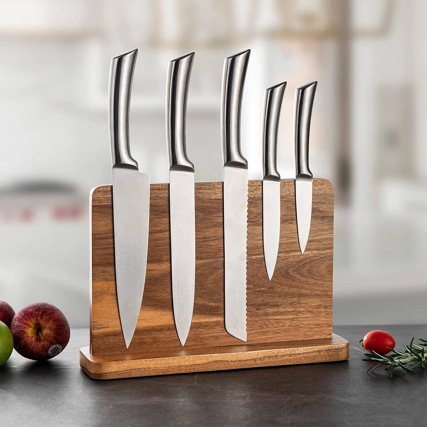Ein Set aus fünf Edelstahlmessern mit unterschiedlichen Klingentypen wird aufrecht in einem Holzblock auf einer Küchenarbeitsplatte ausgestellt.