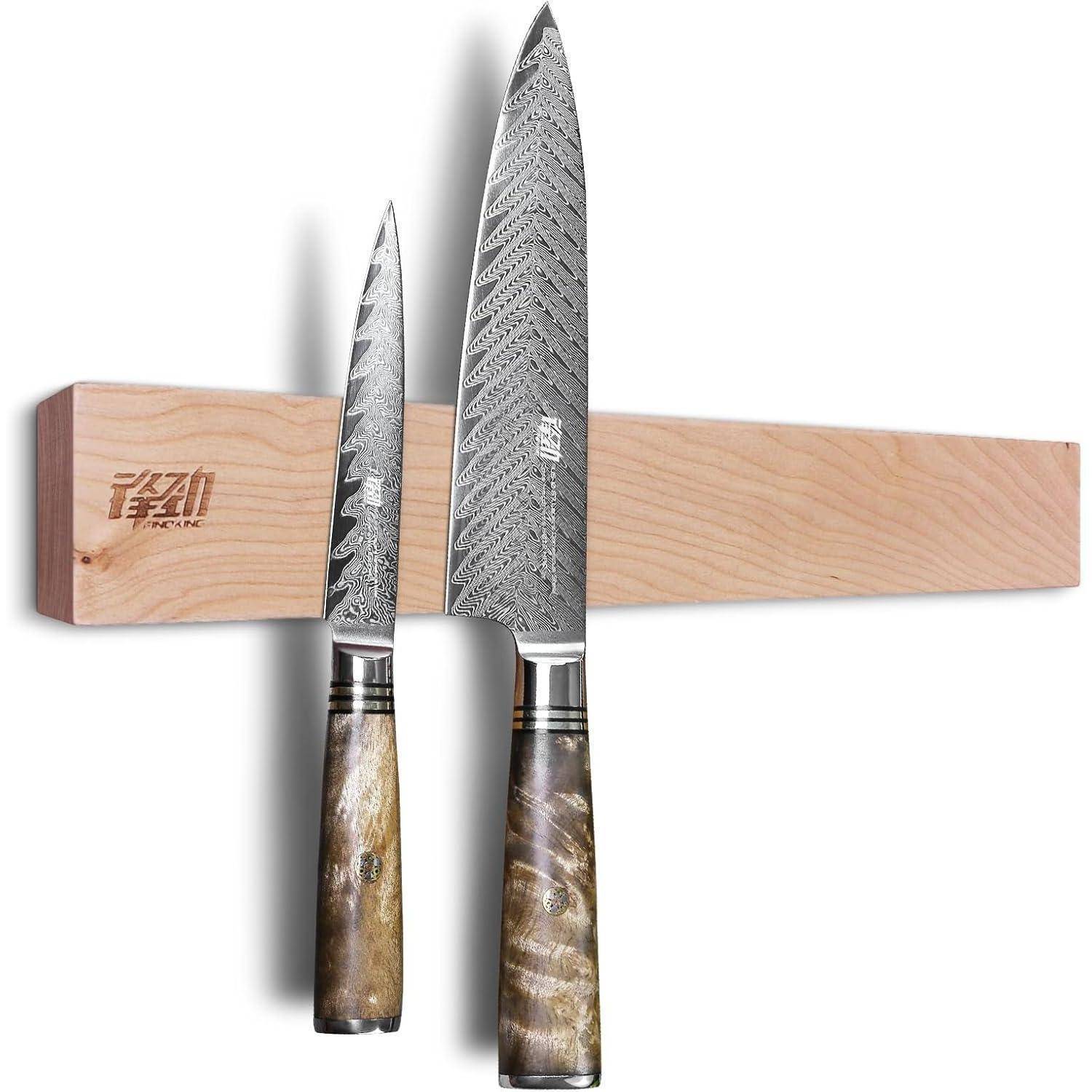 Zwei Küchenmesser mit strukturierten Klingen und dekorativen Griffen sind an einem hölzernen Magnethalter befestigt, der an einer Wand montiert ist.