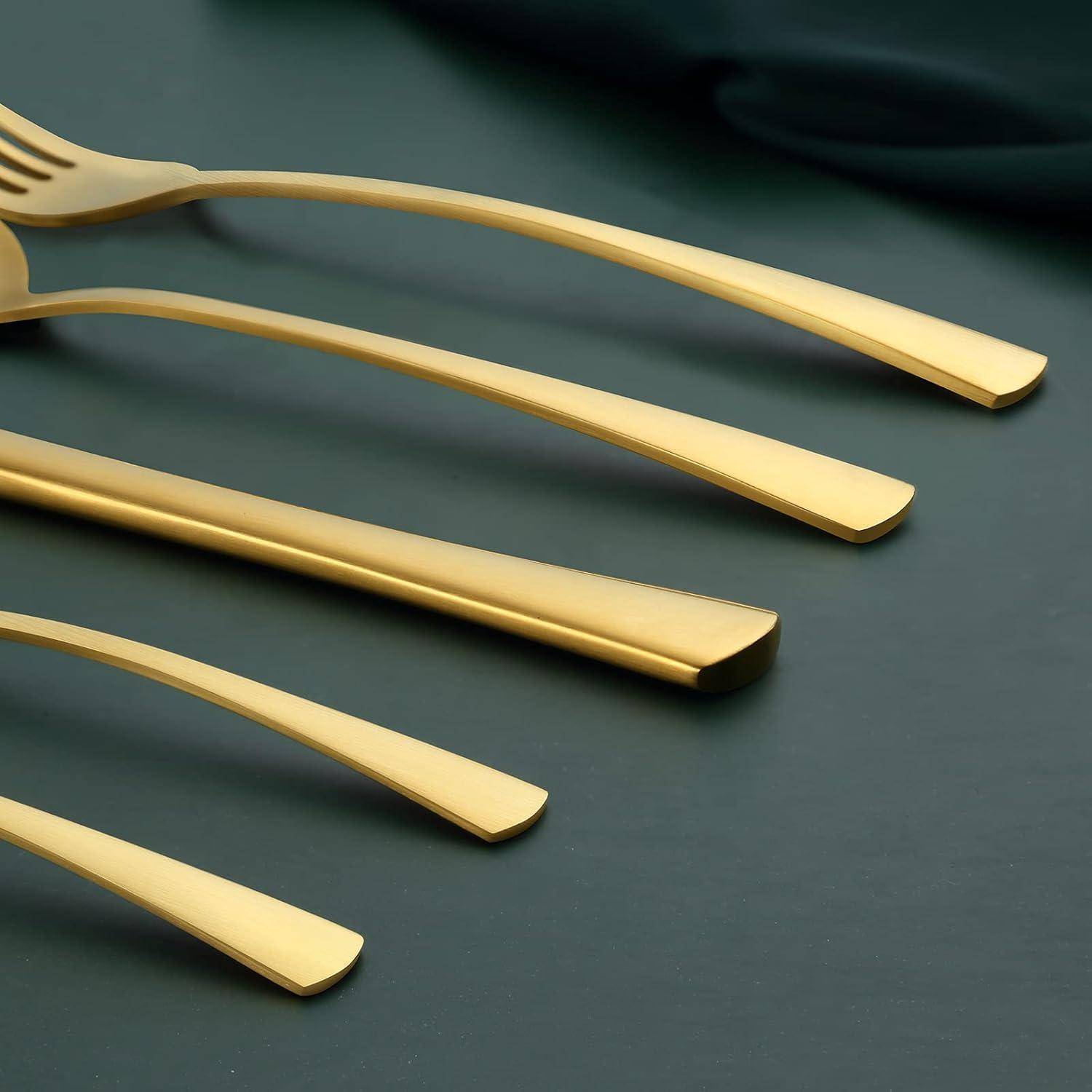 Ein elegantes Besteck-Set in Goldfarben, bestehend aus einer Gabel, einem Messer und einem Löffel, ist kunstvoll auf einer dunklen, glänzenden Oberfläche angeordnet.