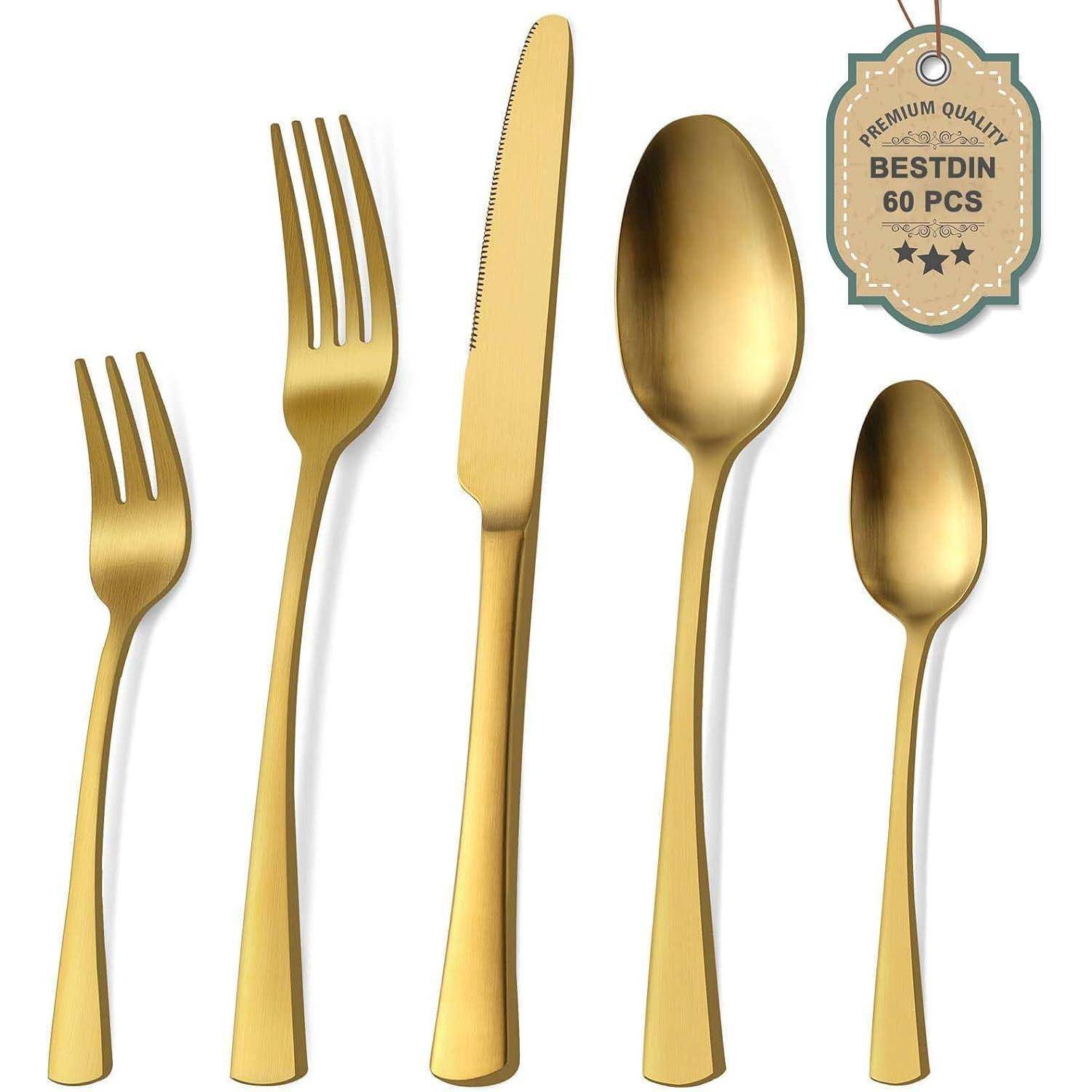 Ein Set Goldflatware, bestehend aus einer Gabel, einem Messer, einem Löffel, einer Dessertgabel und einem Teelöffel. Ein Etikett zeigt: 
