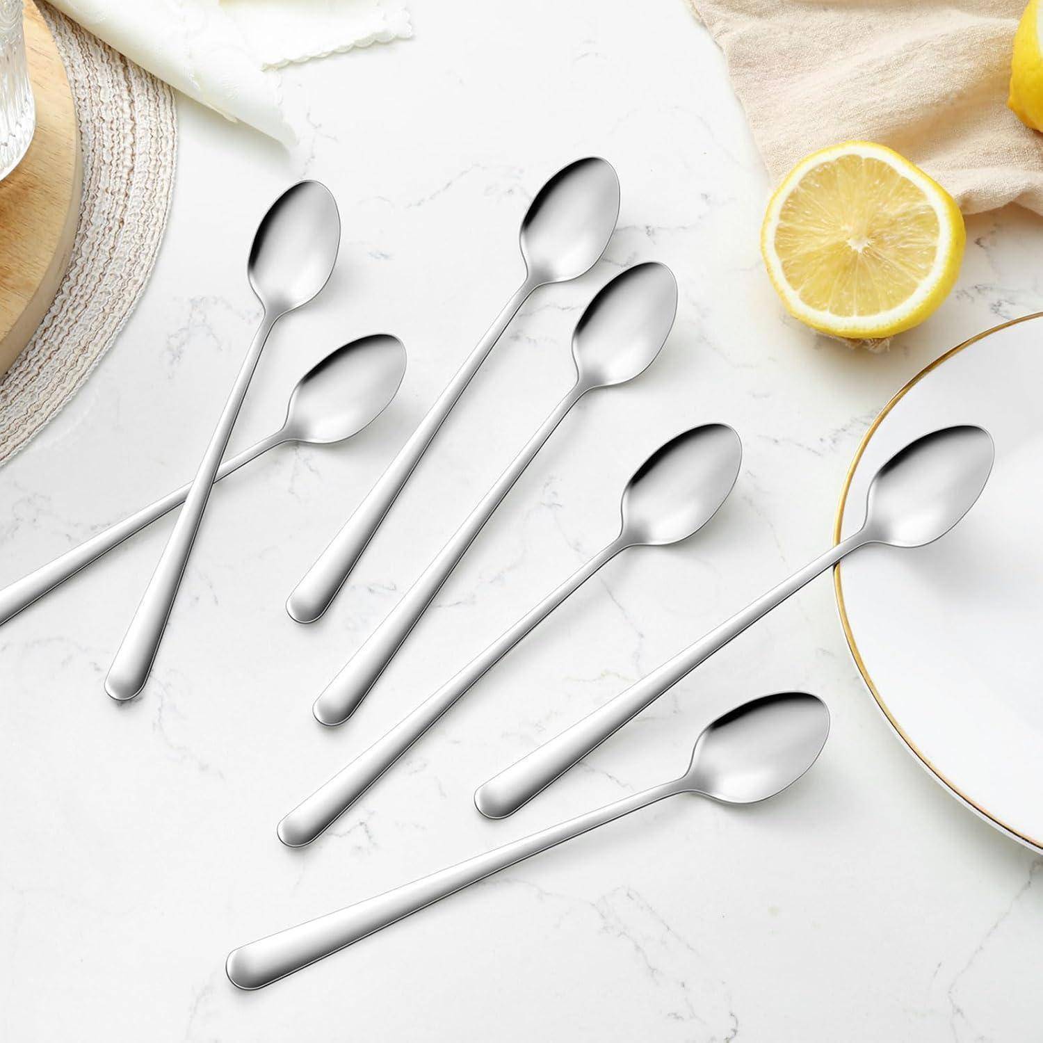 Sieben Edelstahllöffel diagonal auf einer Marmoroberfläche angeordnet, mit einer Zitrone und einem Pastetentuch im Hintergrund.