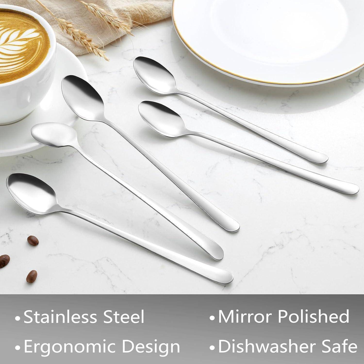 Ein Set aus vier Edelstahllöffeln liegt auf einer Marmoroberfläche neben einem Cappuccino und einem leeren Teller, wobei ihr ergonomisches Design beworben wird.