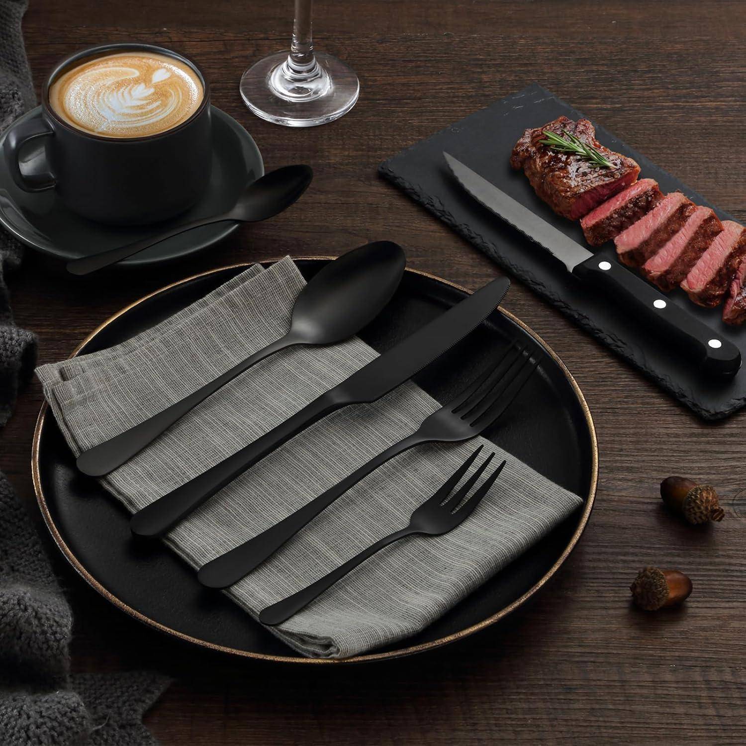 Ein Teller mit Besteck und einer gefalteten Serviette steht neben einem aufgeschnittenen Steak, daneben ein Messer. Eine Tasse Kaffee und ein Weinglas befinden sich in der Nähe.