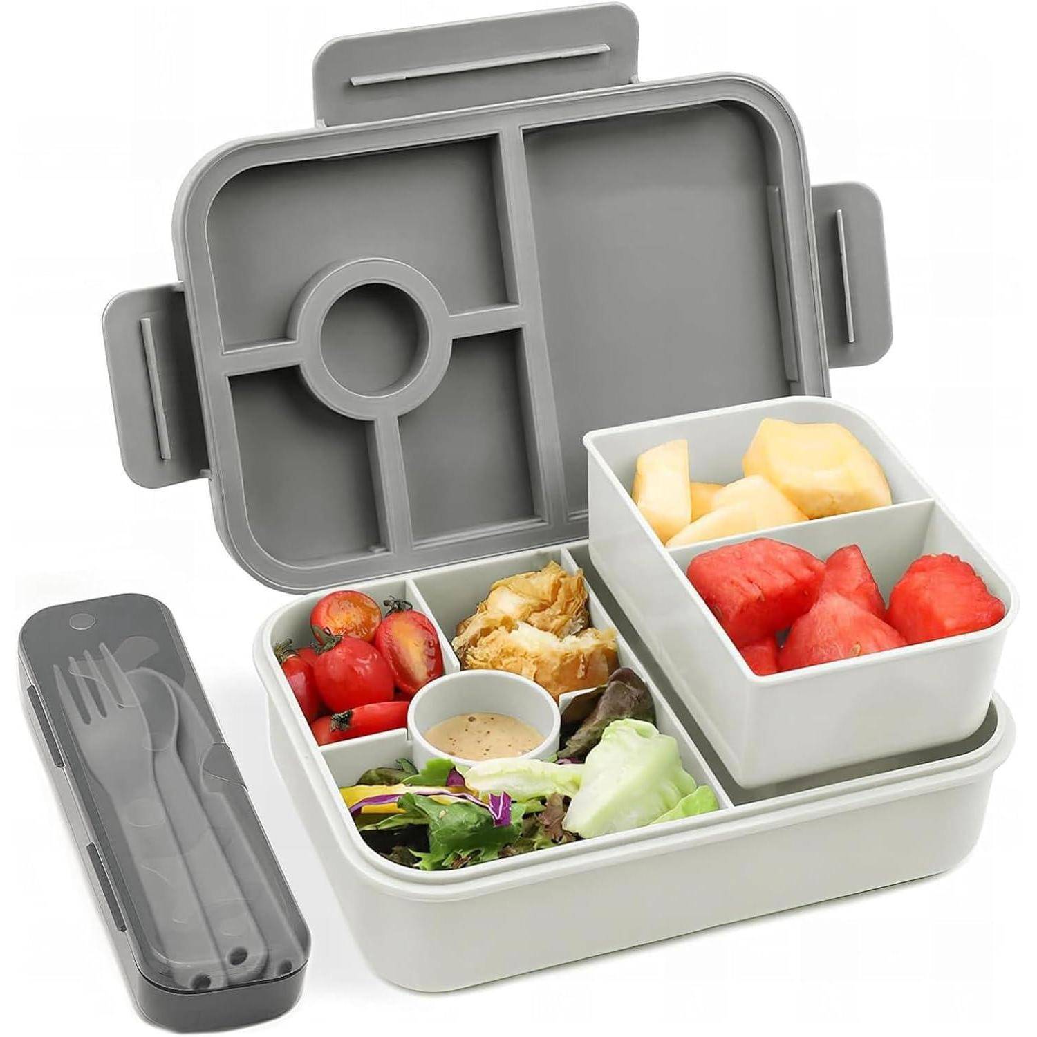 Eine Bento-Lunchbox mit Fächern, die Cherrytomaten, Gurkenscheiben, Salat mit Dressing, gegrilltes Hähnchen und gemischte Früchte enthält.