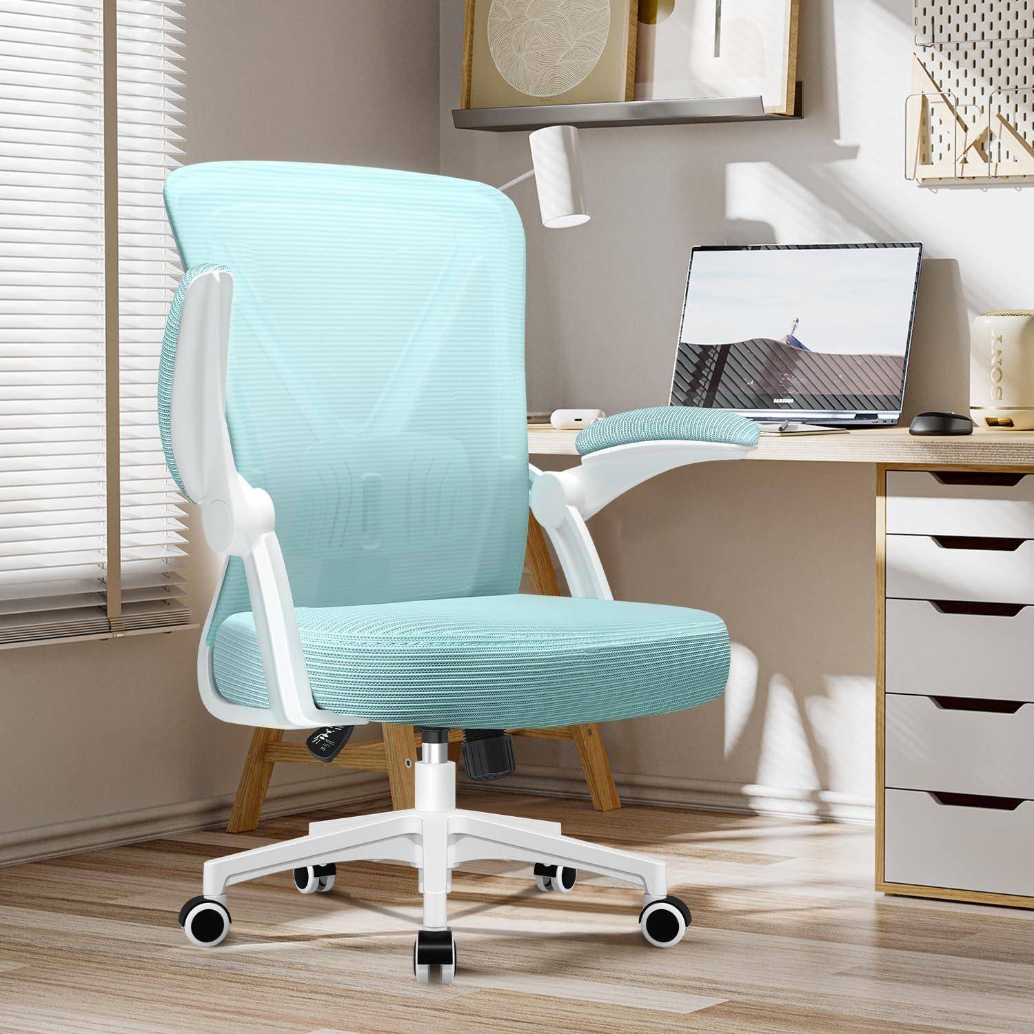 Ein hellblauer ergonomischer Bürostuhl mit weißen Akzenten steht neben einem modernen Schreibtisch in einem hellen Homeoffice.