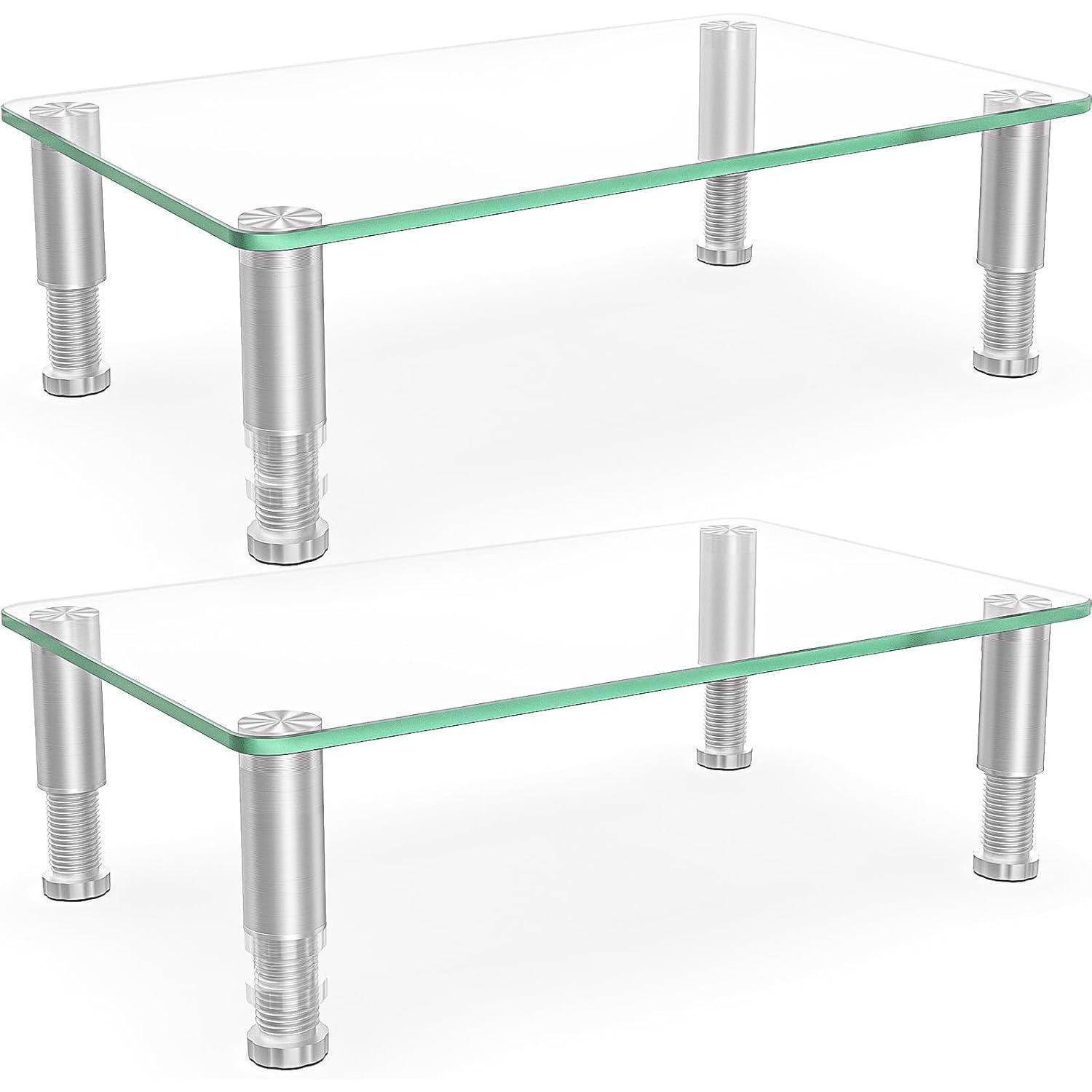 Zwei Monitorständer aus Glas mit verstellbaren Metallbeinen übereinander gestapelt, die deren Verwendung zur Erhöhung von Bildschirmen auf einem Schreibtisch veranschaulichen.